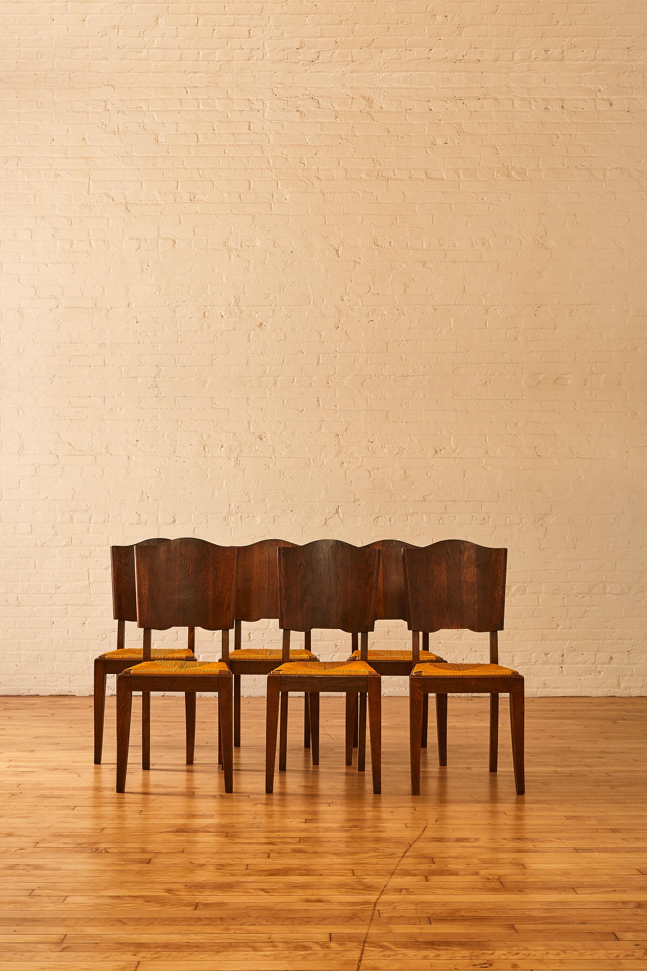 A set of 6 French oak and rush dining chairs featuring a modern scalloped solid wood backrest. The backrest shape promotes a modern edge to the sturdy and well made oak frames.

 