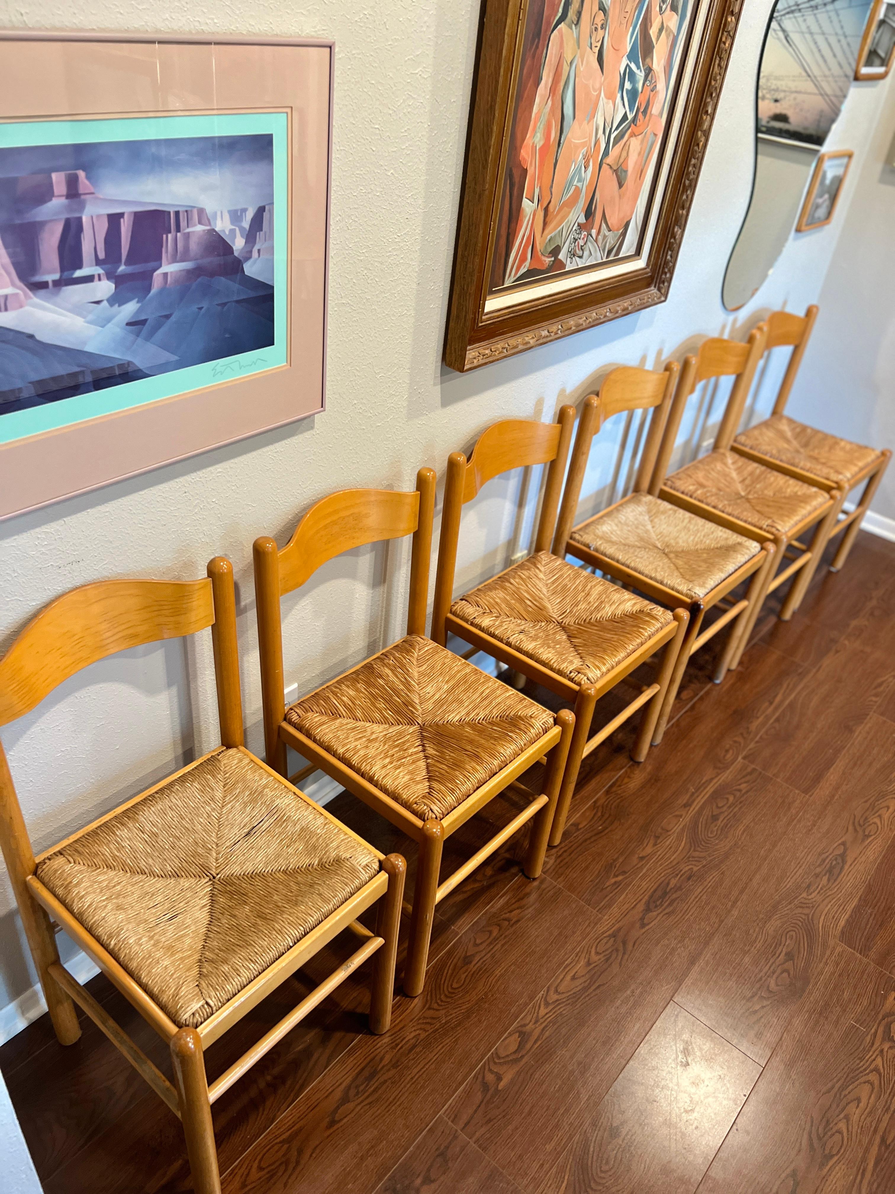 A set of 6 vintage chairs in rush and solid wood frames, circa 1970s. These chairs feature open backs with horizontal slat designs. They are meticulously handcrafted, showcasing a simple yet elegant style with a touch of modern organic aesthetics.