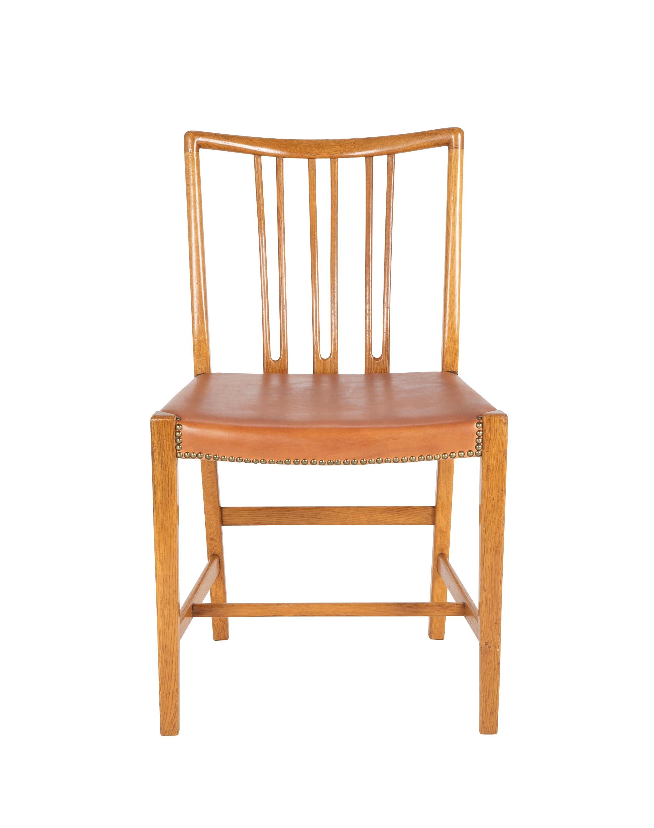 A set of 8 Hans Wegner bleached mahogany dining chairs with cognac leather seats with nail head trim. With mark to underside of apron.
