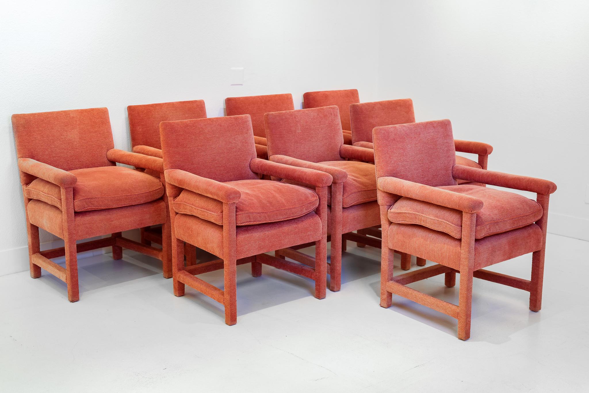 This is a set of 8 fully upholstered dining chairs that came from the estate of James Garner. The chairs are upholstered in a textured salmon colored fabric. The backs, legs, arms, and supporting pieces are all upholstered. The cushion is attached