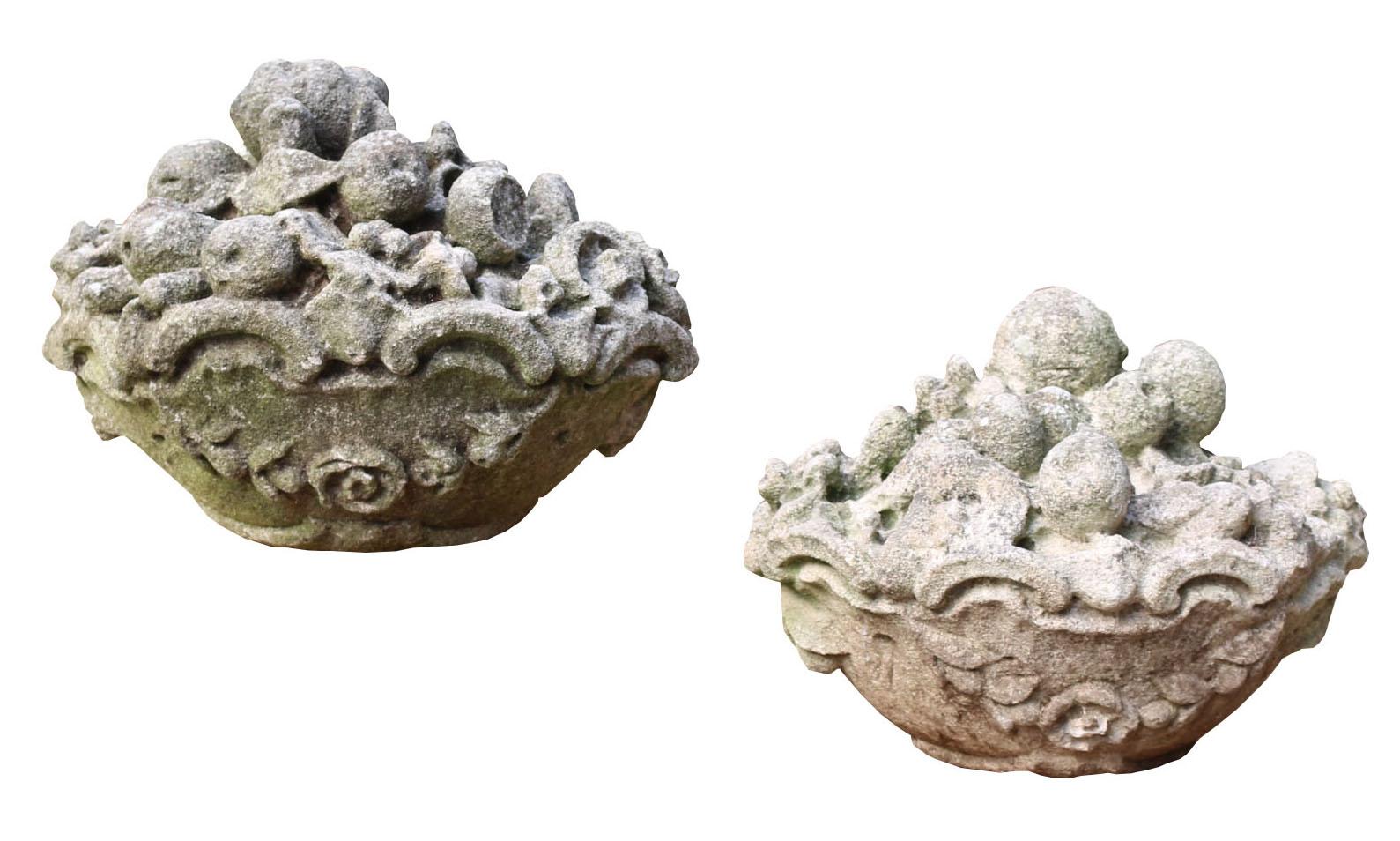 A pair of oval shaped limestone carved baskets of fruit. These were reclaimed from a garden in South London. lovely weathered condition, with great detail.