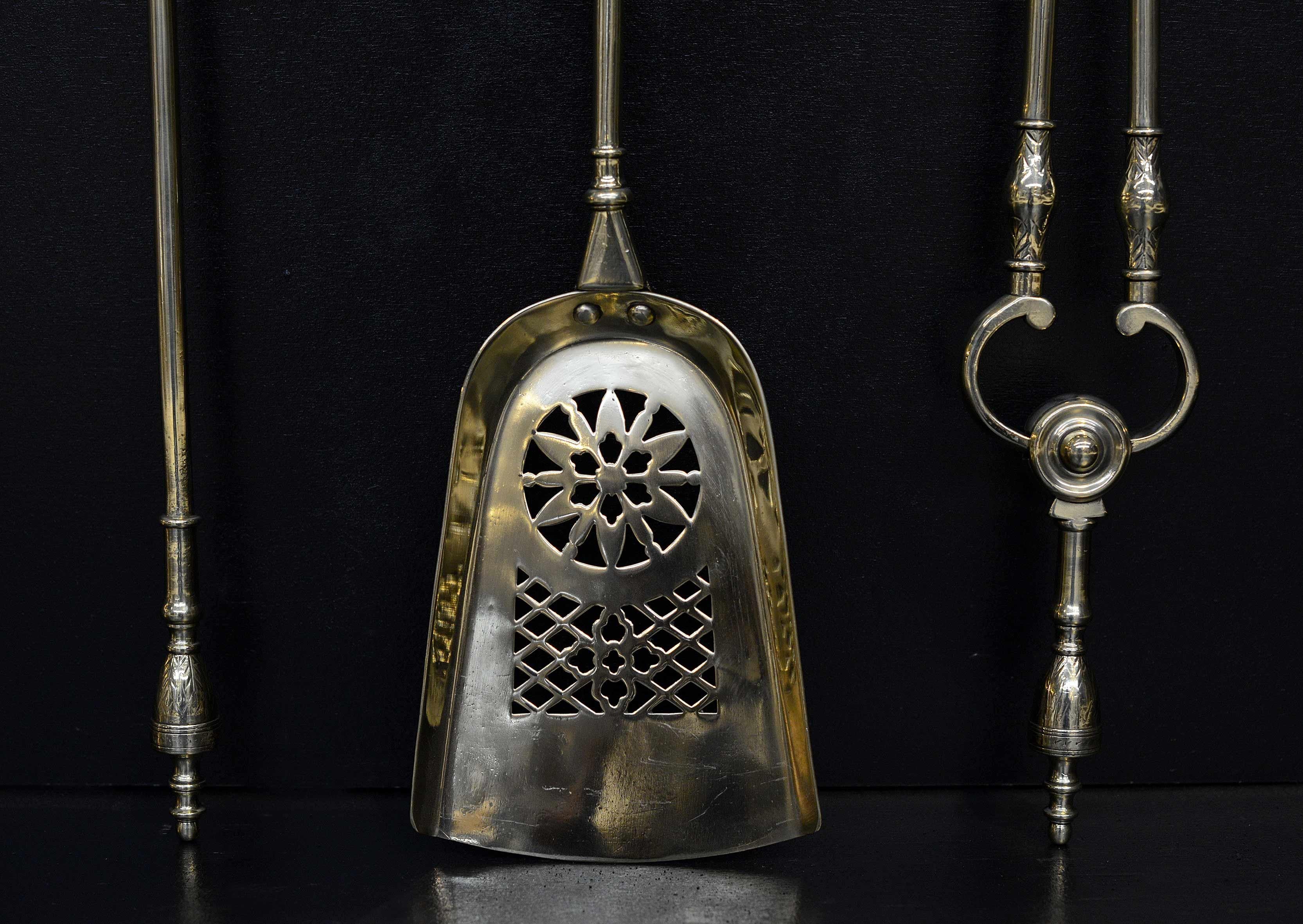 A set of three brass firetools. The pierced shovel with floral paterae design surmounted by engraved urn finials. English, 19th century.

Length:	710 mm      	28