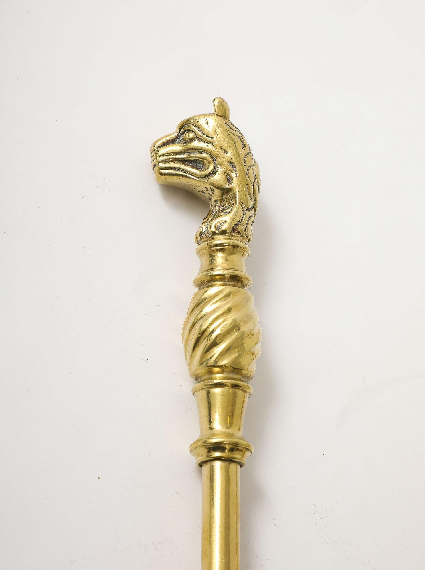 Set of Edwardian brass fire tools having cast leopard handles, pierced shovel and iron poker