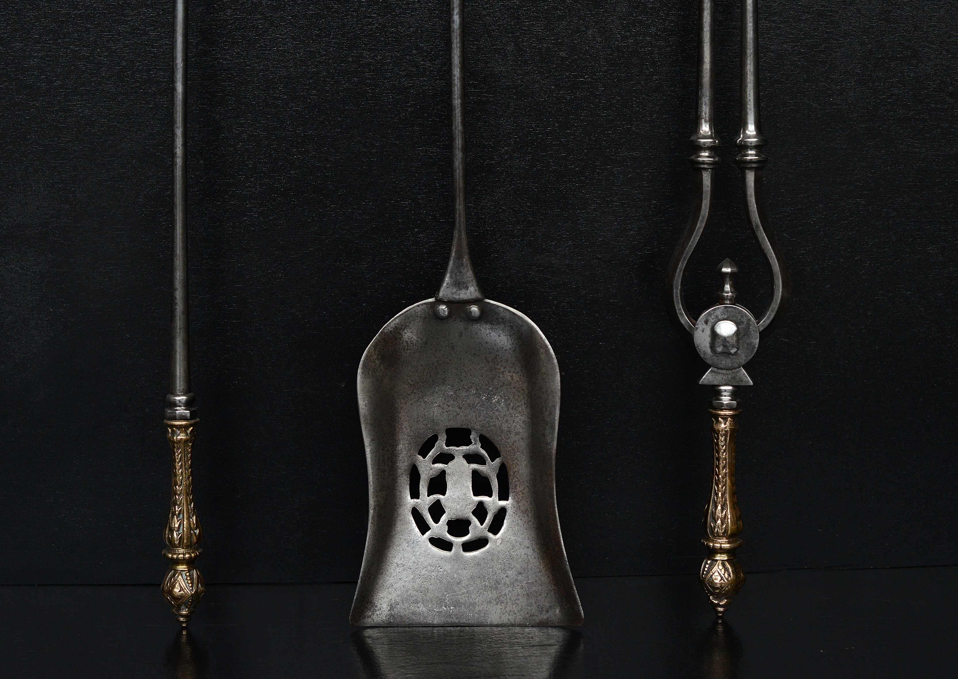 A set of 19th century English firetools. The steel shafts surmounted by decorative cast brass handles adorned with bell flowers. Pierced shovel.

Length:	720 mm      	28 ⅜