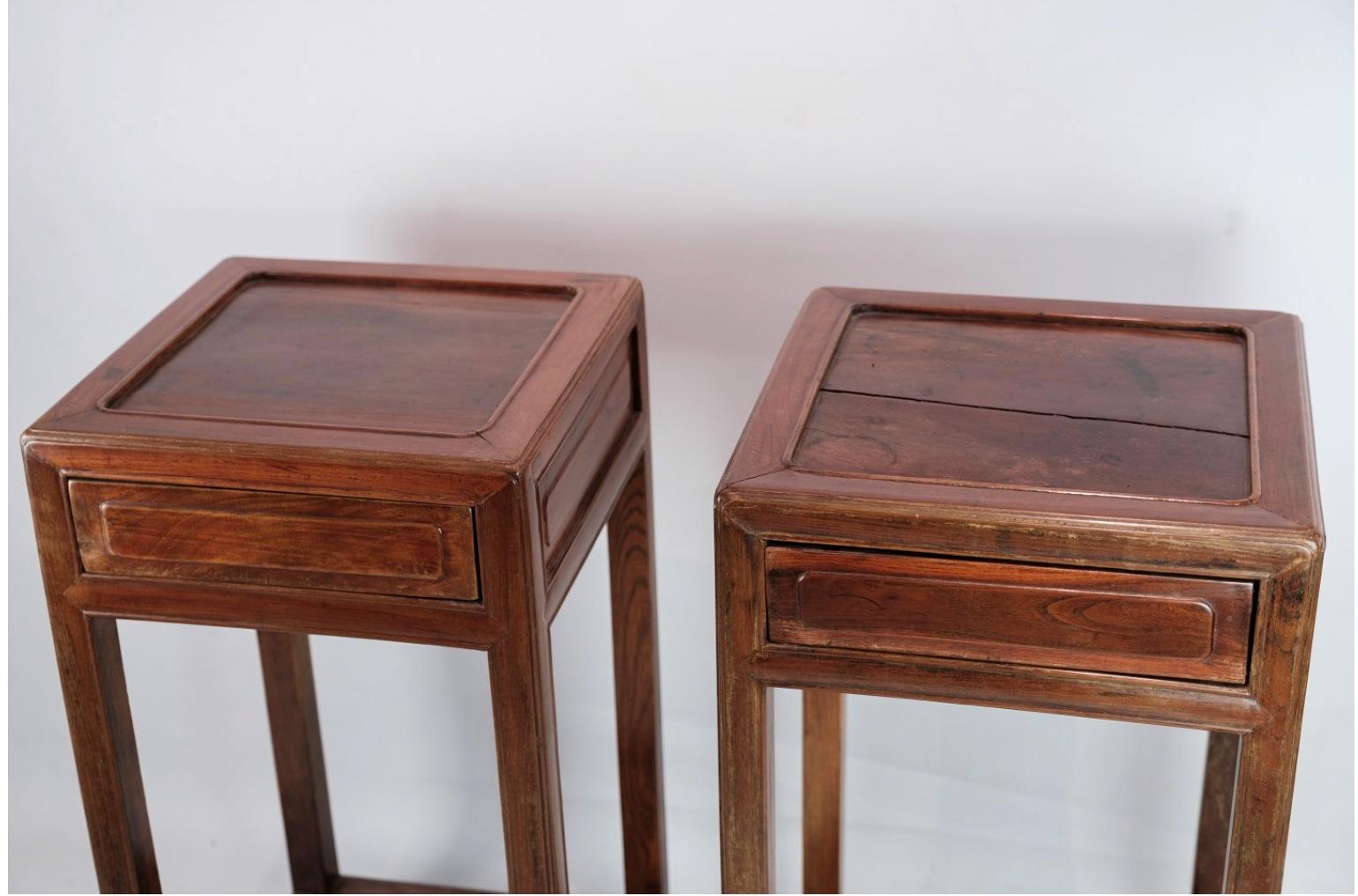 The set of Chinese side tables with drawers, crafted from polished dark wood and dating back to the 1880s, is a captivating blend of elegance and historical charm. These tables exemplify the exquisite craftsmanship and intricate detailing