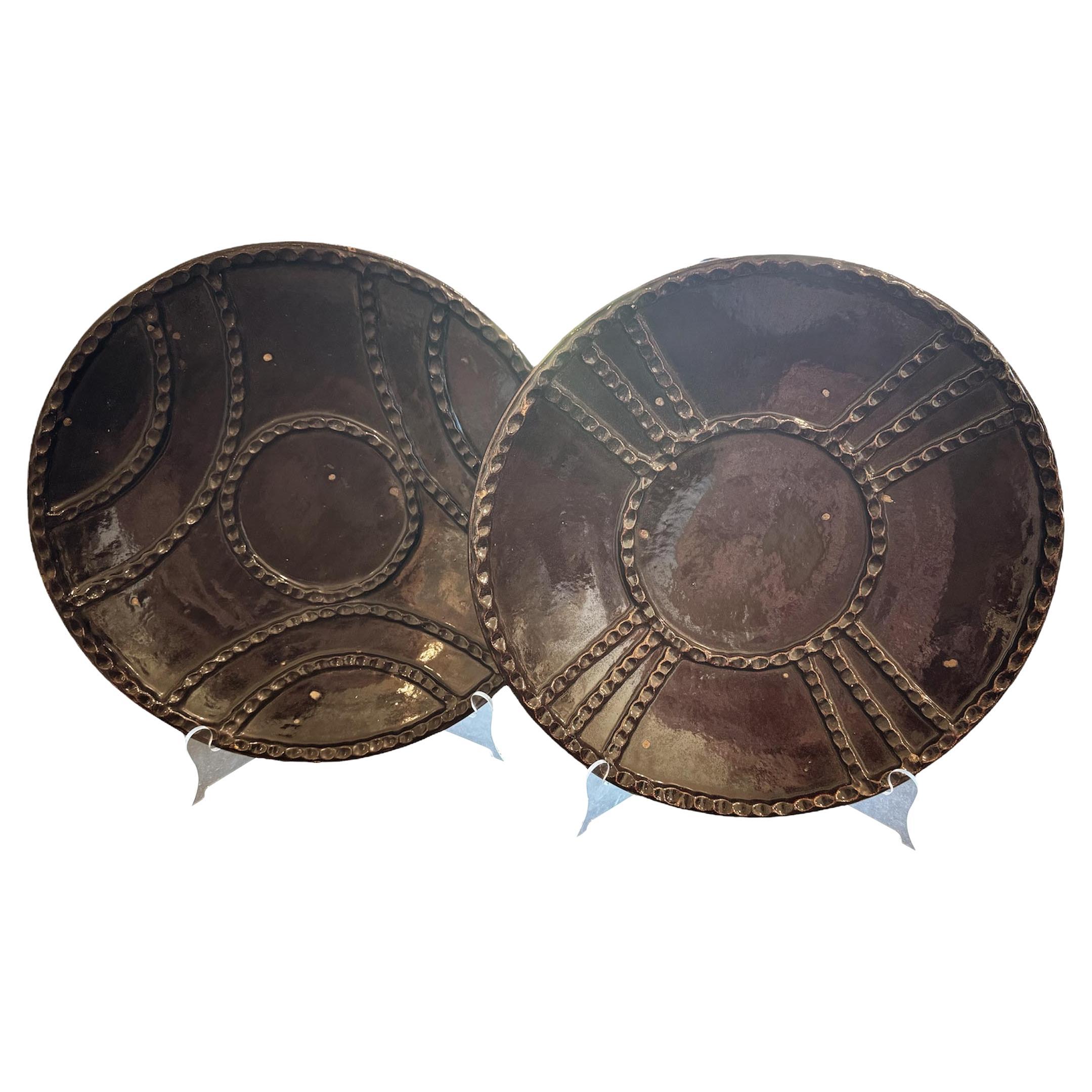 For sale is a captivating set of Formations Castano plates, featuring both round and radius styles that offer a unique blend of artistic design and functionality. Crafted from high-quality ceramic, these plates showcase a warm ebony finish with a