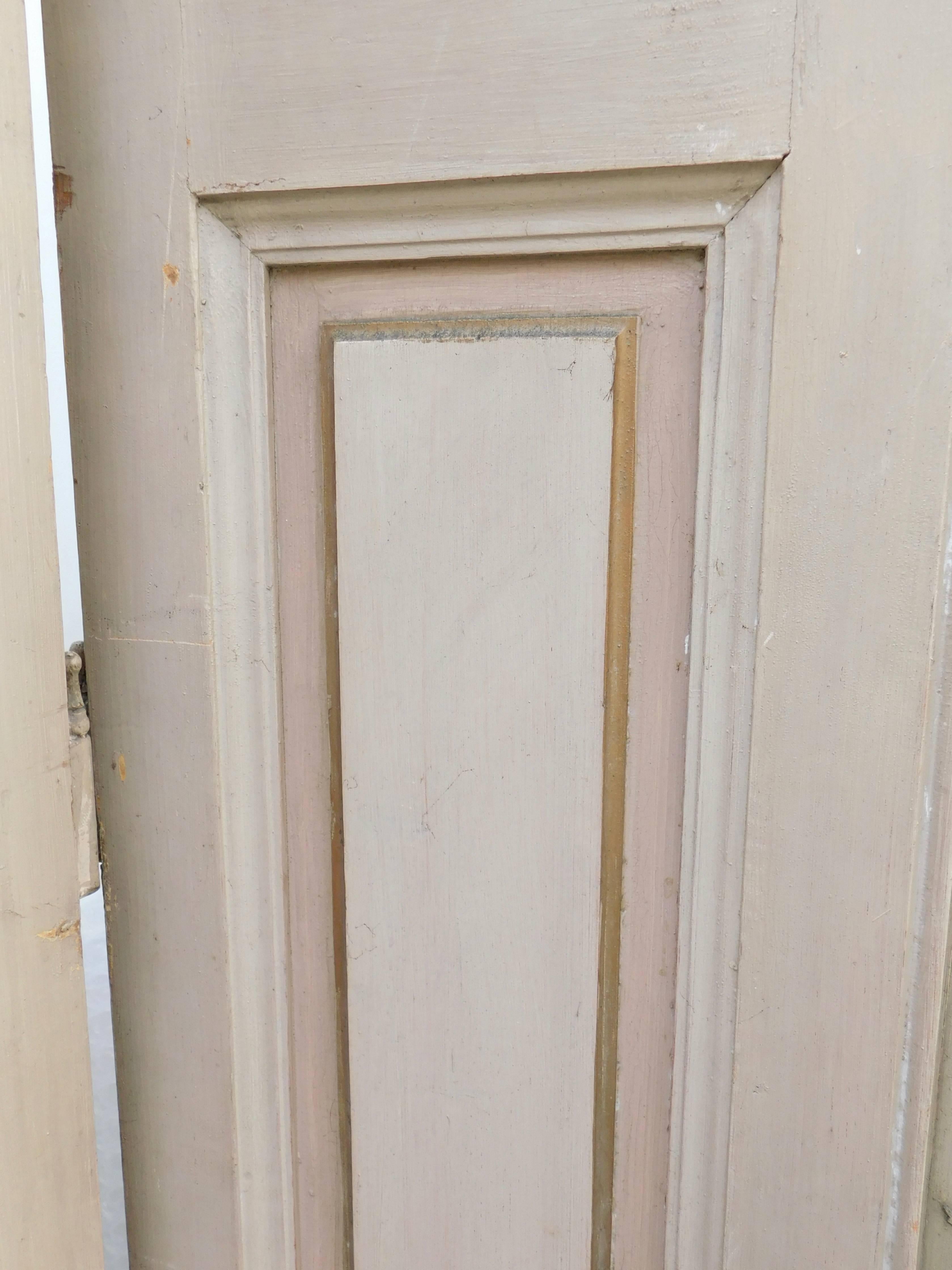 Early 19th century French door shutters retaining the original soft beige, light salmon and gold paint. We have two sets of eight shutters each, for a total of 16 matching shutters (eight pair).Each pair are hinged together, and of course you could