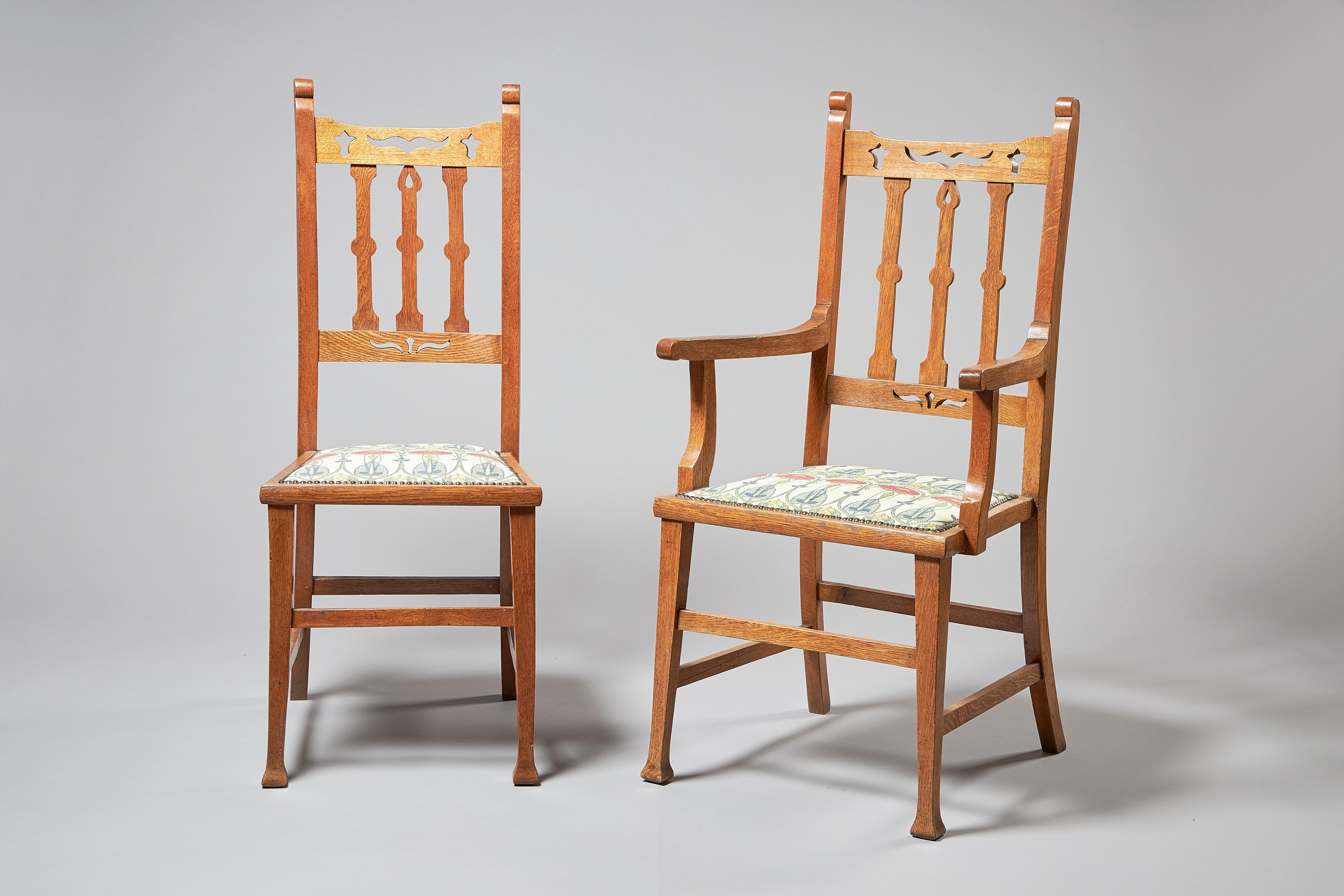 A set of eight Arts & Crafts oak dining chairs, including two carvers, with squared arms, early 20th century, circa 1900-1910, with latticed backs and carved details, the seats upholstered in Charles Rennie Mackintosh 'Belle Epoque' fabric.