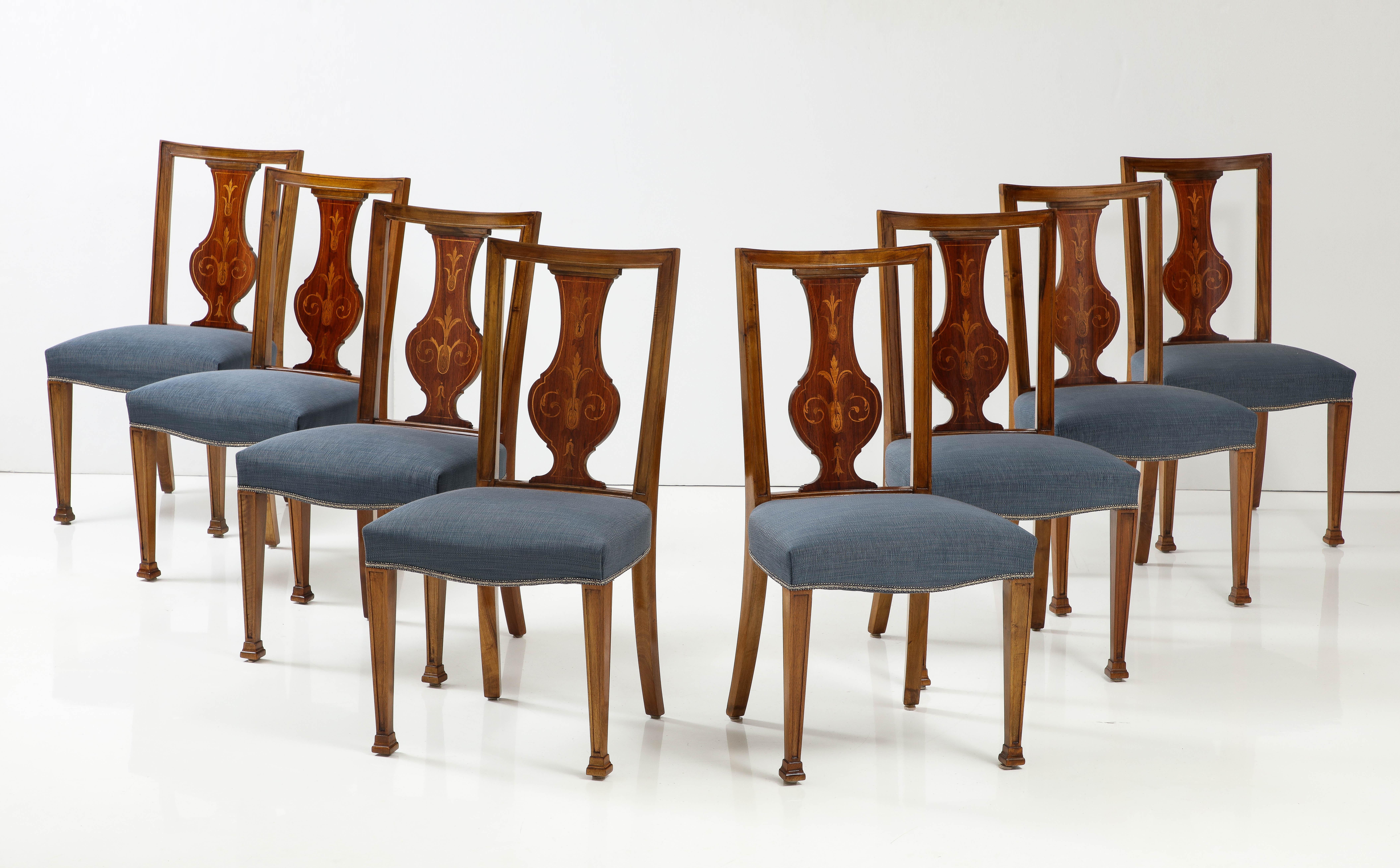A set of eight Baltic Neoclassical style walnut sidechairs with fruitwood inlays, Circa 1910s, each with a channeled rectangular backrest, baluster form back splat with fruitwood inlays, tight upholstered seats raised on square tapered and channeled