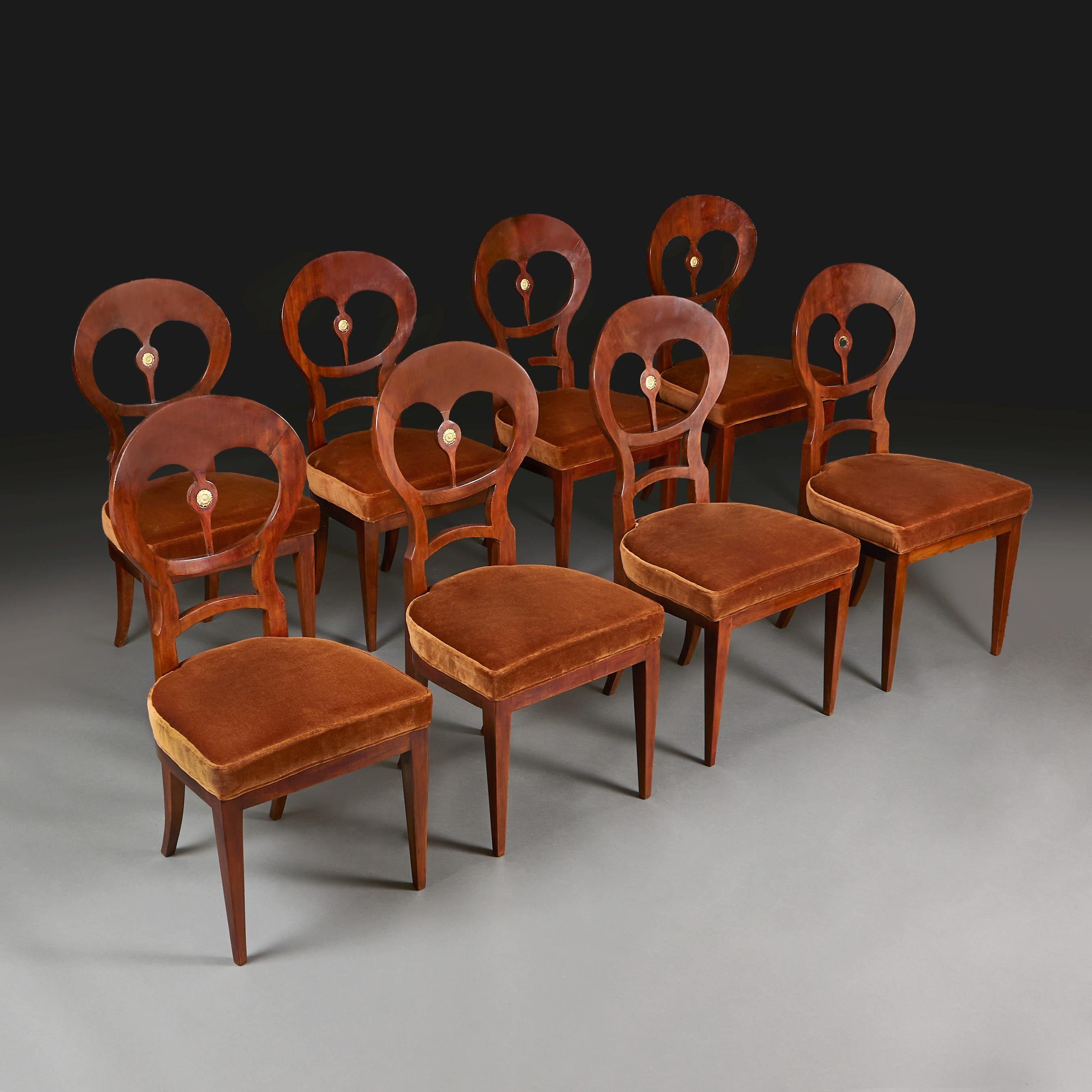 Austria, circa 1820

A fine set of eight Biedermeier walnut dining chairs, with rounded and pierced backsplats, embellished to the centre with an ormolu sunflower paterae. The seats upholstered in brown velvet. 

Measures: Height 98.00cm
Width