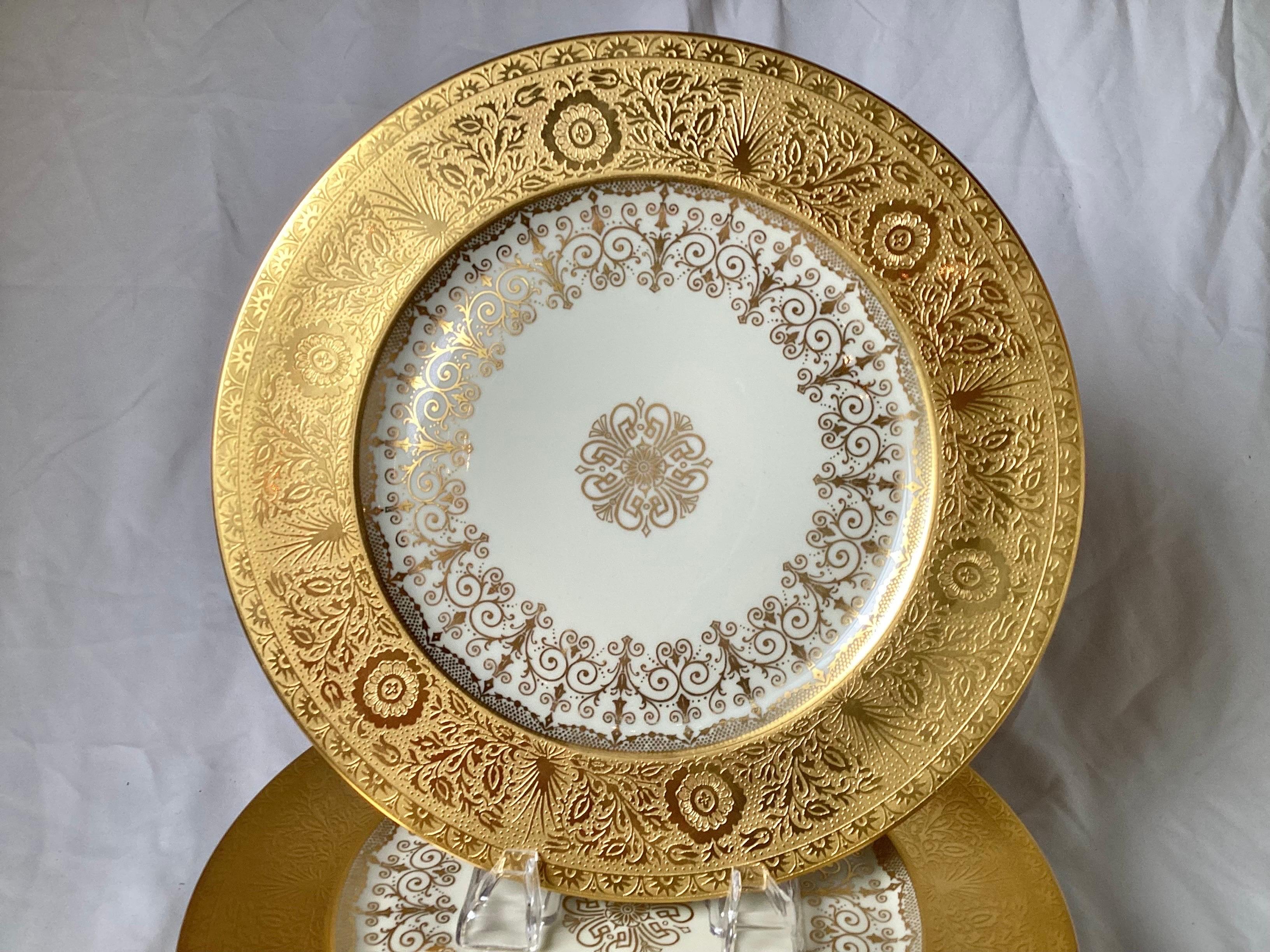 A set of eight opulent heavy gold encrusted service plates. The broad gold borders with center gilt decoration, each is 11 inches in diameter.