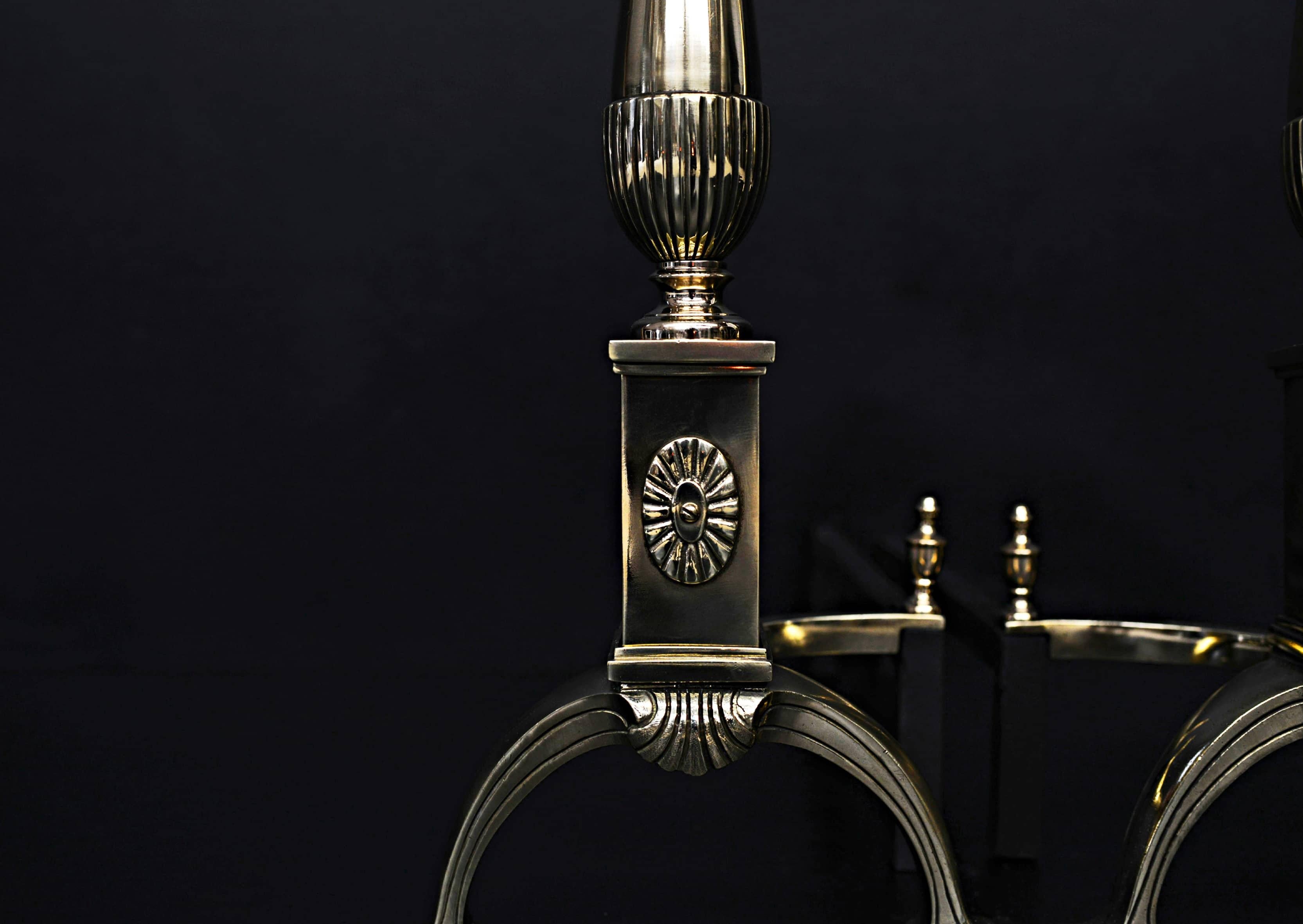 A set of English brass firedogs. The arched feet with rosette patarae above surmounted by elegantly tapering uprights and urn finials. Circa 1900.  

Height:	550 mm      	21 ⅝