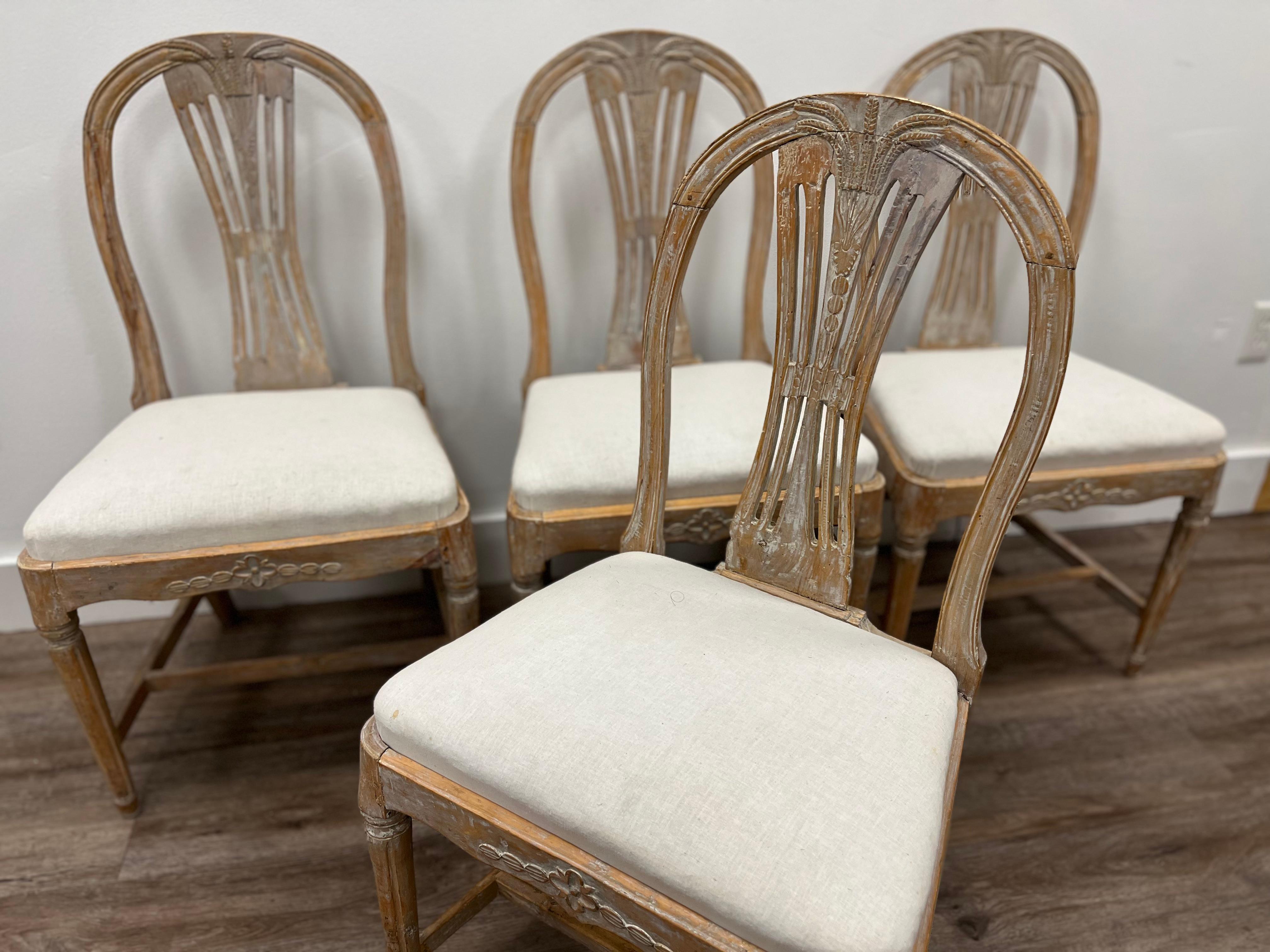 A set of four 19th century Swedish Late Gustavian Ax (also known as Vase) chairs from Lindome featuring a balloon-shaped back with five vertical, interconnected slats. In the center, five ears of wheat form a bouquet on the crest that fan outward. A