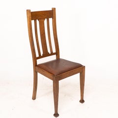 A set of four Arts and Crafts oak dining chairs with comfortable shaped backs
