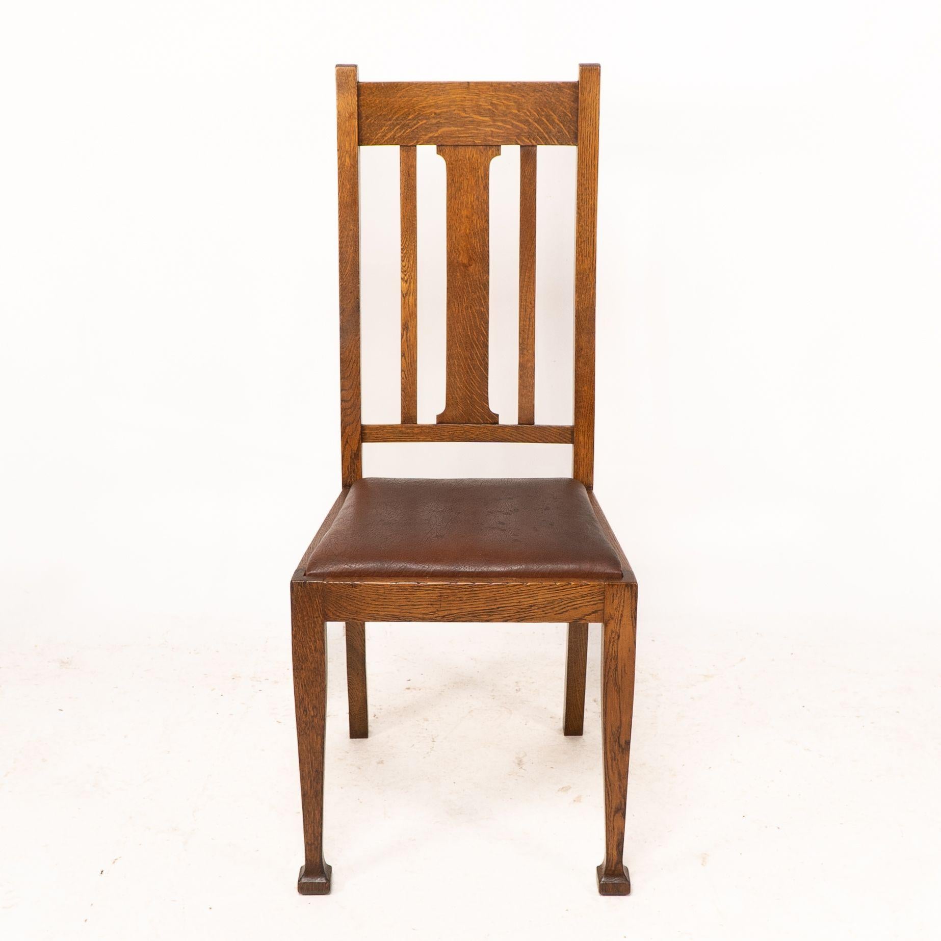 Anglais Un ensemble de quatre chaises de salle à manger en chêne de style Arts and Crafts avec des dossiers de forme confortable. en vente