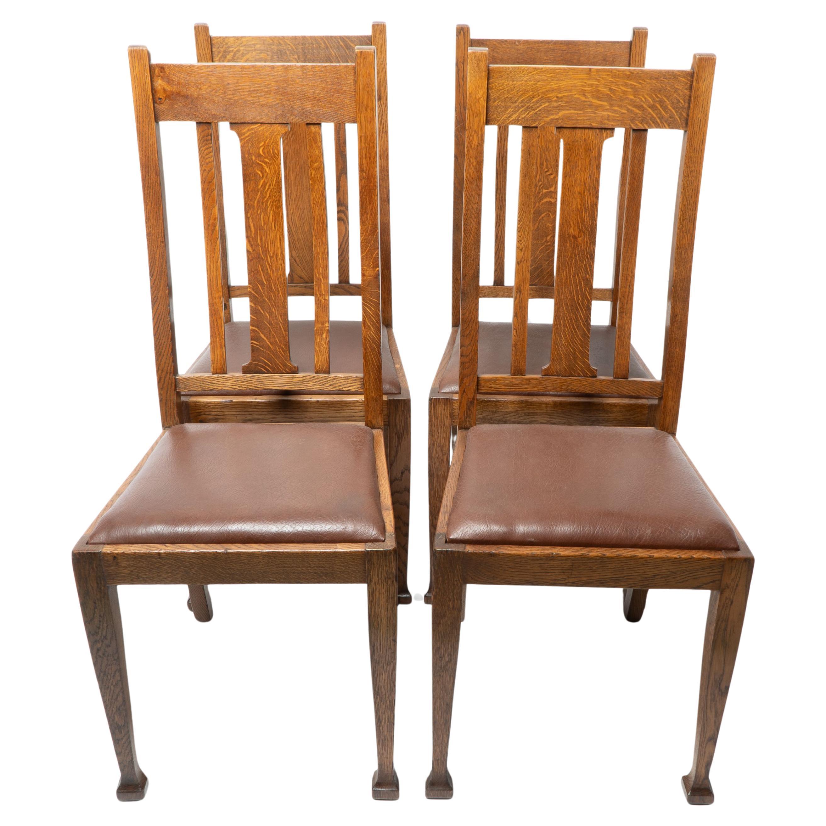 A set of four Arts and Crafts oak dining chairs with comfortable shaped backs