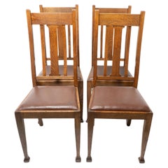 Un ensemble de quatre chaises de salle à manger en chêne de style Arts and Crafts avec des dossiers de forme confortable.