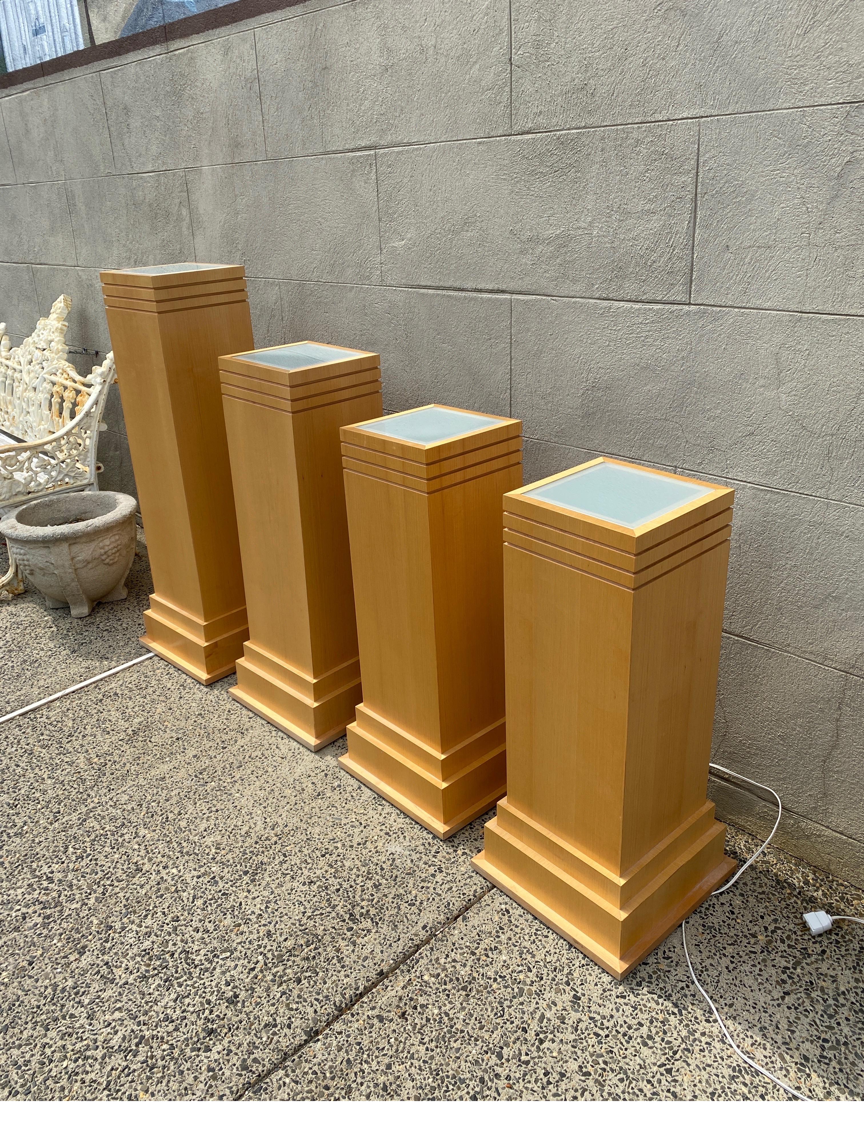 A set of four graduated birch wood lighted pedestals. The square shape with a frosted glass top panel with light under. 
 The bases are stepped out plinth shape. These can be used separately and lighted, or plugged into each other The tallest, 41