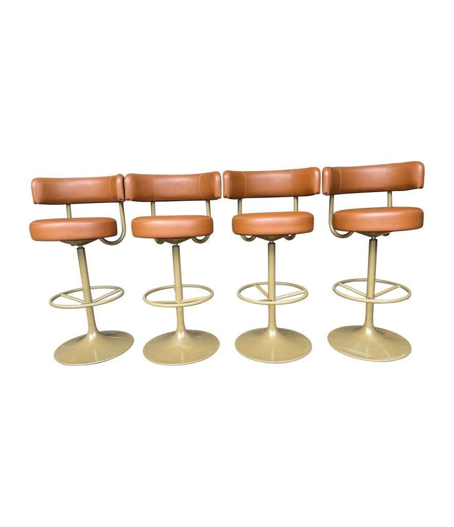 A set of four Börje Johanson “Jupiter” swivel bar stools in cognac faux leather and gold lacquered metal base, with foot rest. In very good condition with orignal 