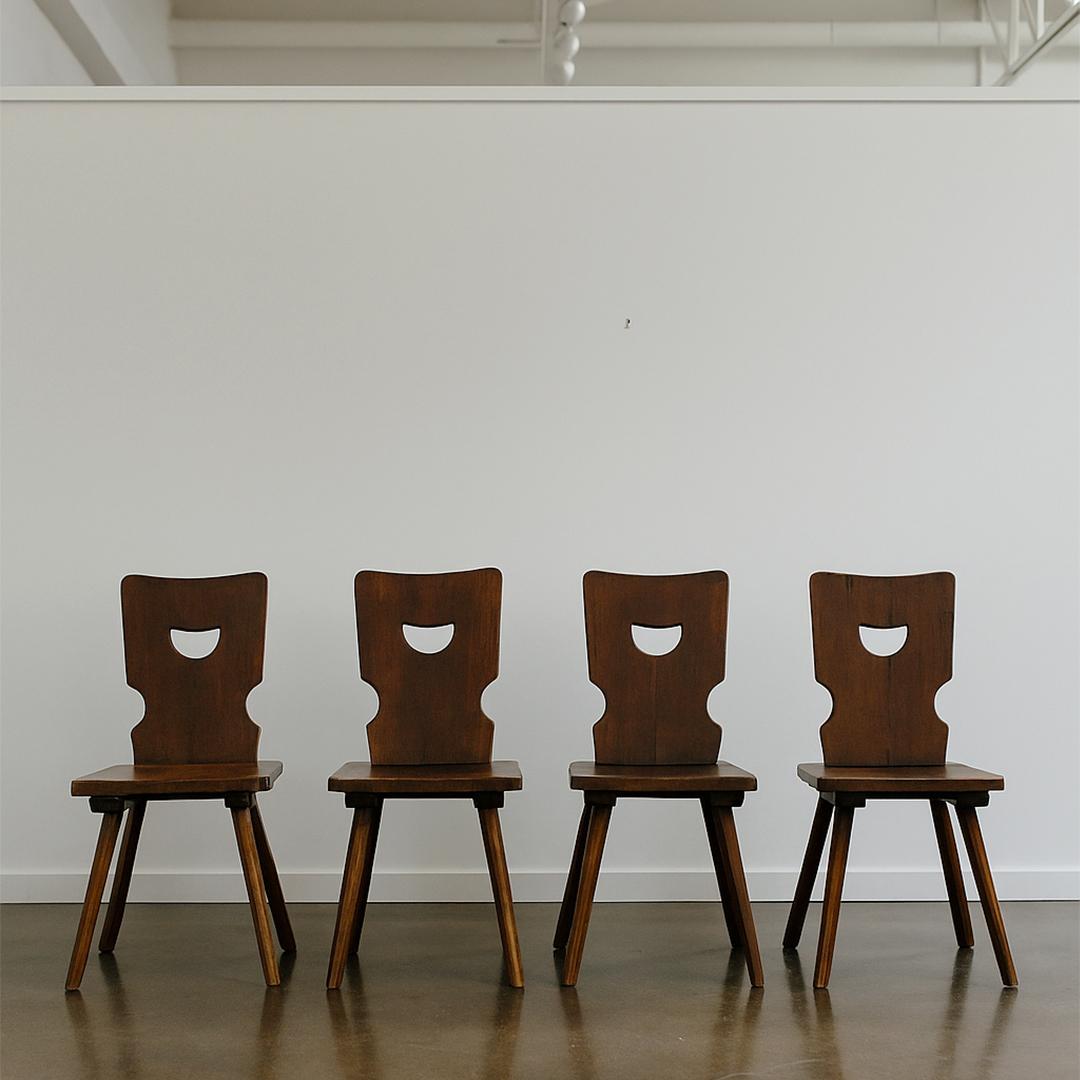 Un set scultoreo di quattro sedie da pranzo brutaliste nello stile del produttore belga Torck. Realizzato in legno massiccio con schienali a mezzaluna intagliati e gambe angolari, il design riflette la semplicità architettonica e grezza tipica