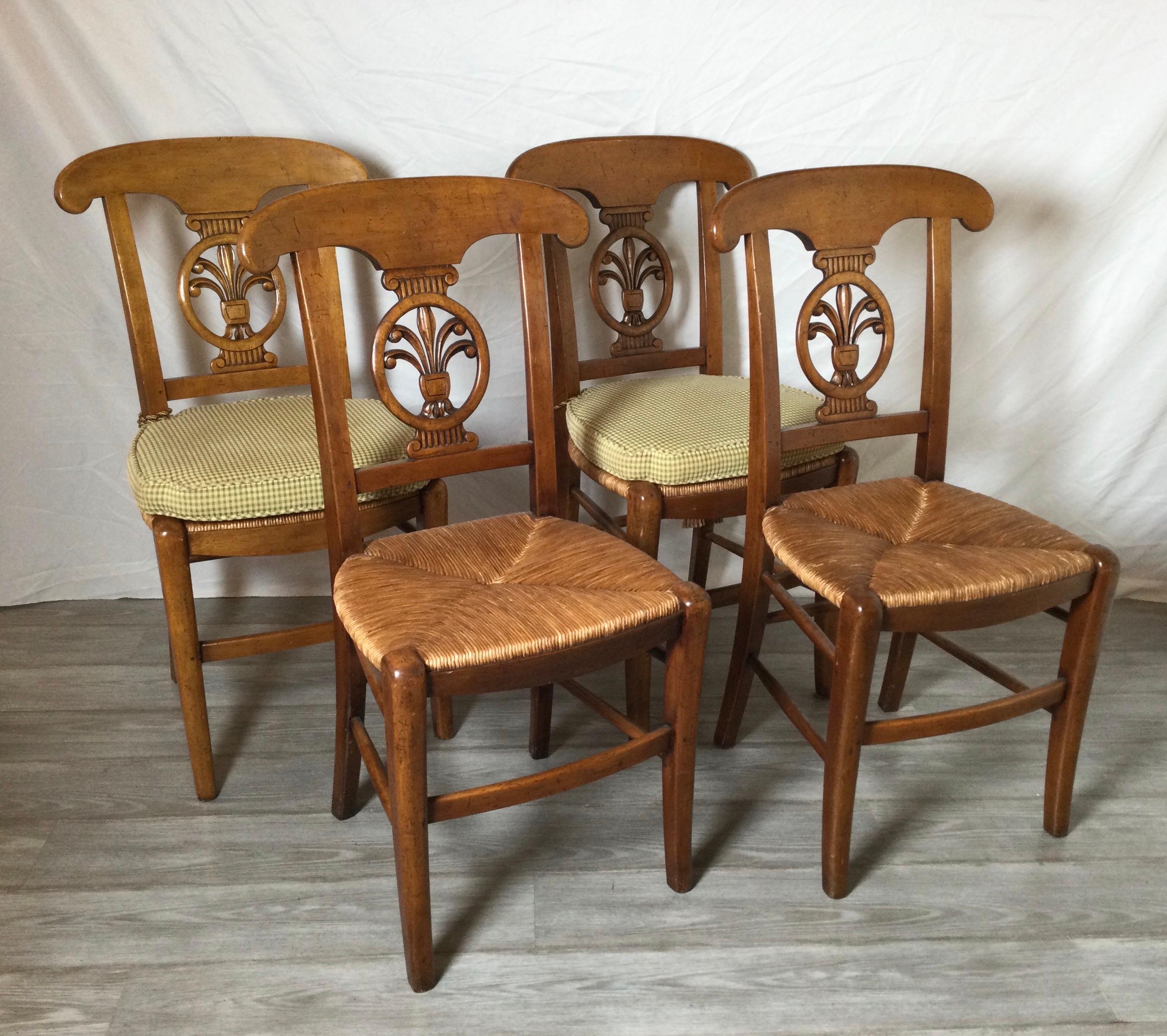 A charming set of four country French side chairs in hand carved fruitwood with rush seats. Cushions included.