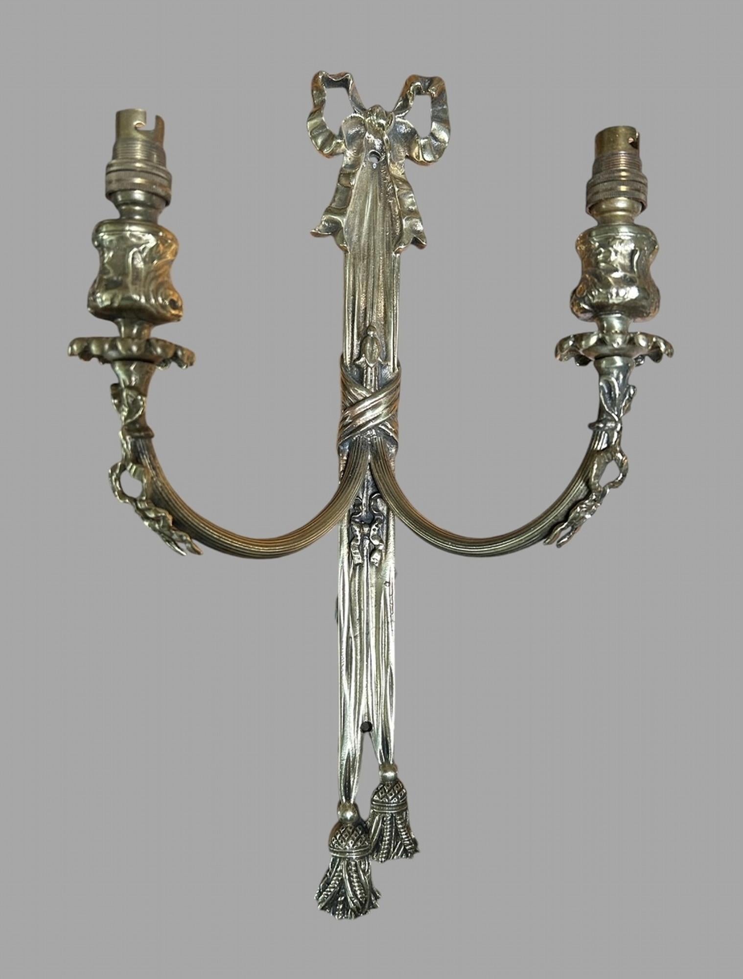 A Set of Four Highly Decorative Mid 20thc Wall Double Light Sconces with decorative detail with bow to top and tassel below. Originally purchased from Jean Munro, London. In excellent condition and wired ready to go up.
Jean Munro: Interior designer