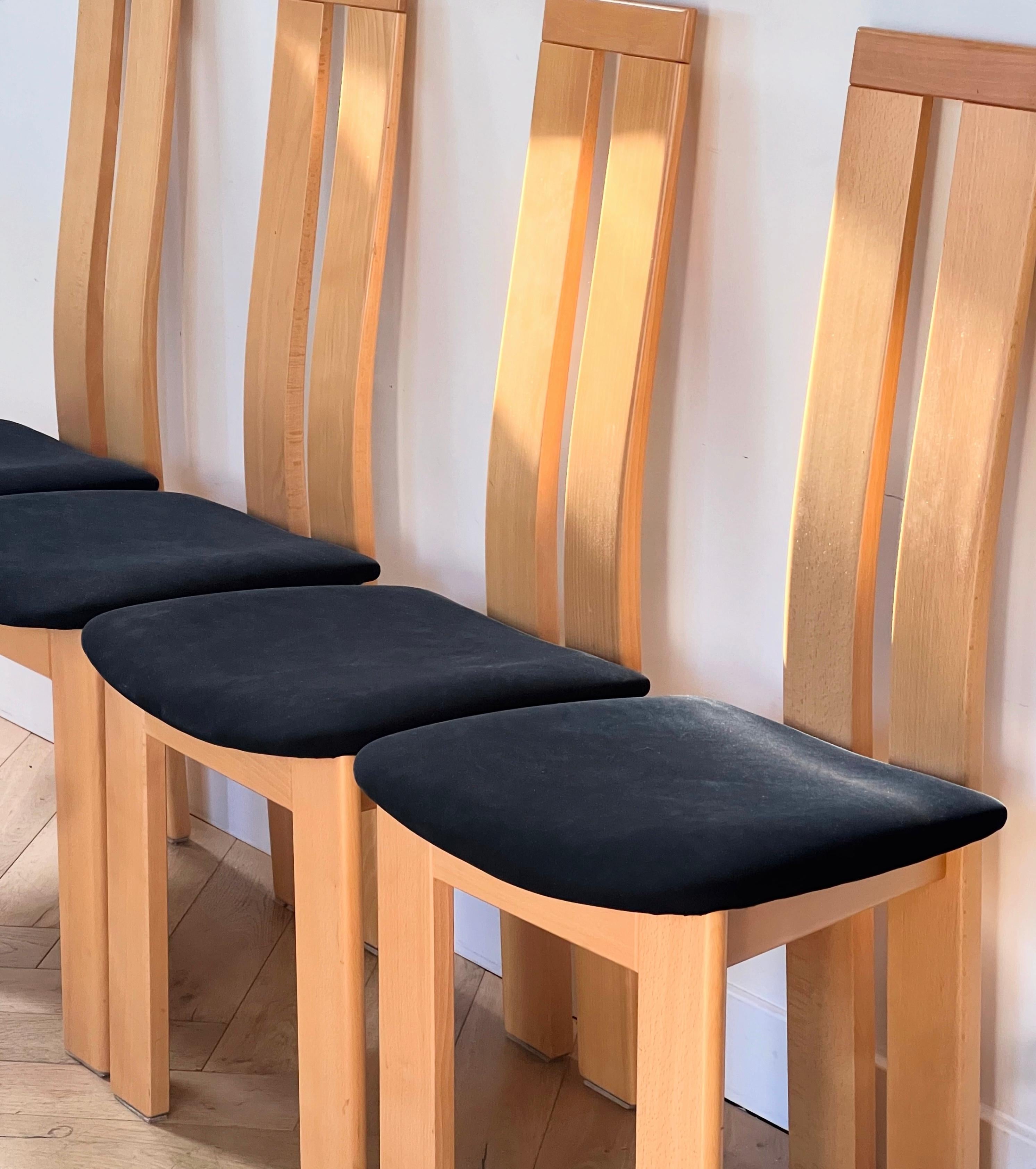 A set of four dining chairs by Pietro Costantini for Ello Furniture, Italy late 20th century. In rich yet subtle beechwood with black microsuede seats, and featuring the classic Costantini curve in the back rest, these chairs are unique and at once