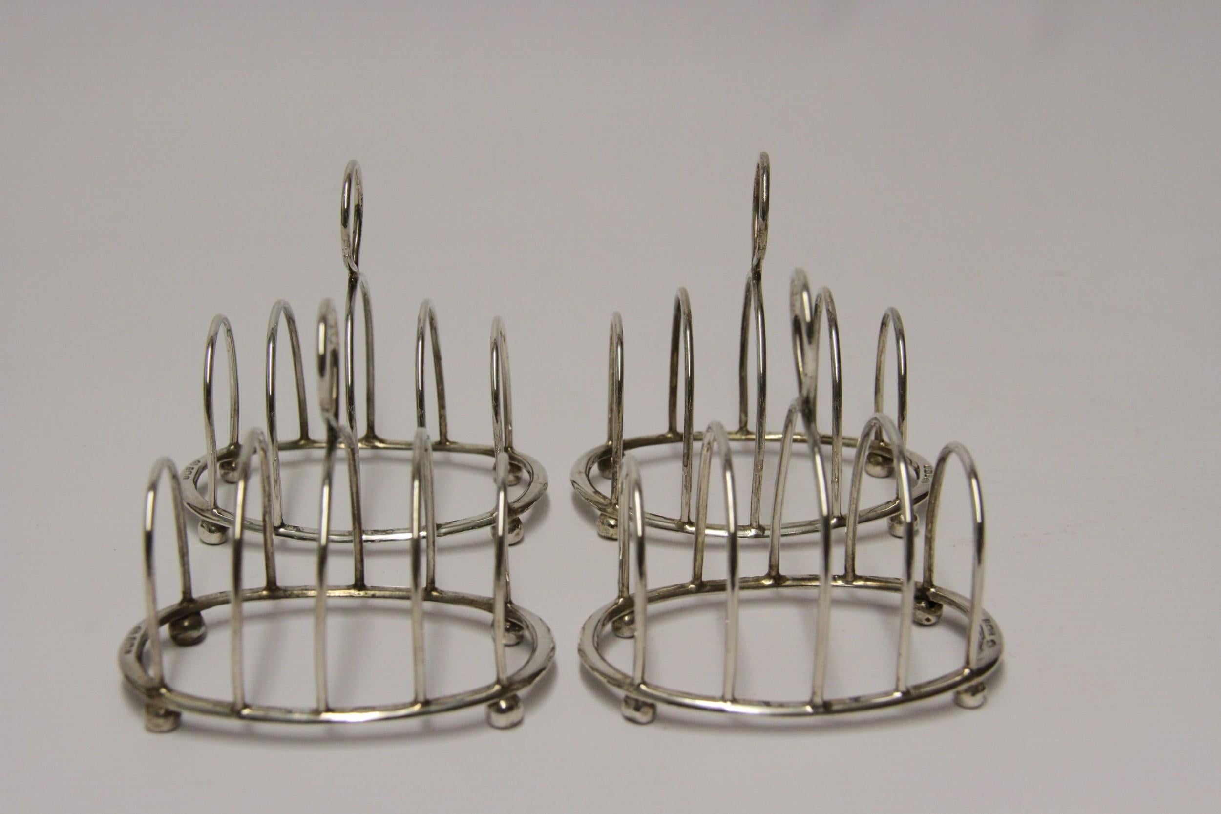 A delightful set of four solid silver toast racks made to a simple oval design with ball feet and loop handles for lifting. These very usable toast racks were made for single place settings as they are quite small. They are in good condition with no
