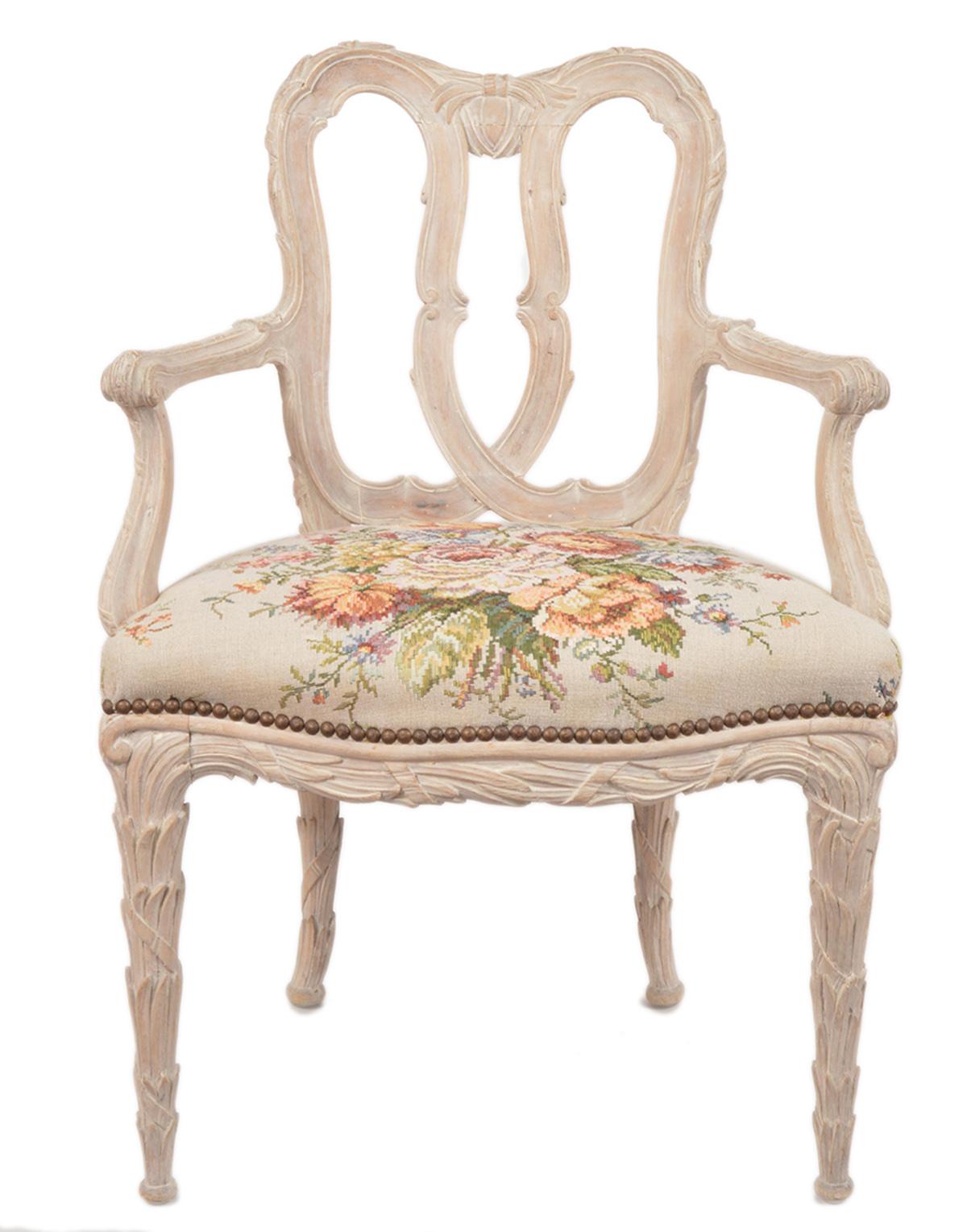 A group of four charming Louis XV style armchairs richly carved with leaf work on legs, backrests and armrests. The chairs are painted in a washed way letting the wood shine through. The seats are upholstered and covered with a woven fabric