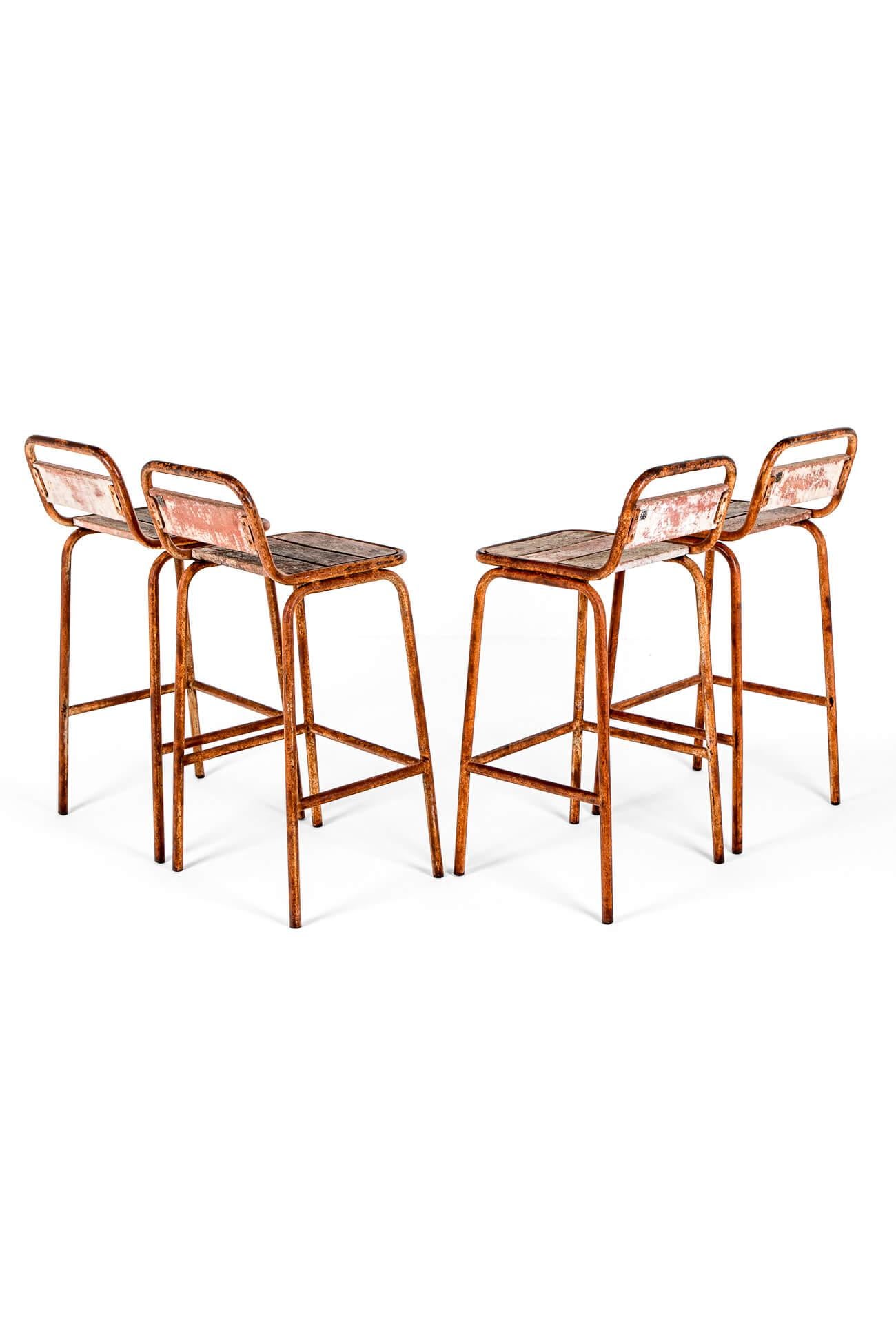 A vintage set of four tall industrial stools with steel frames and oak slatted plank seats.

The seats have low curved oak backs with gently curved frames united by three peripheral stretchers to the base.

Wonderful remnants of orange paint