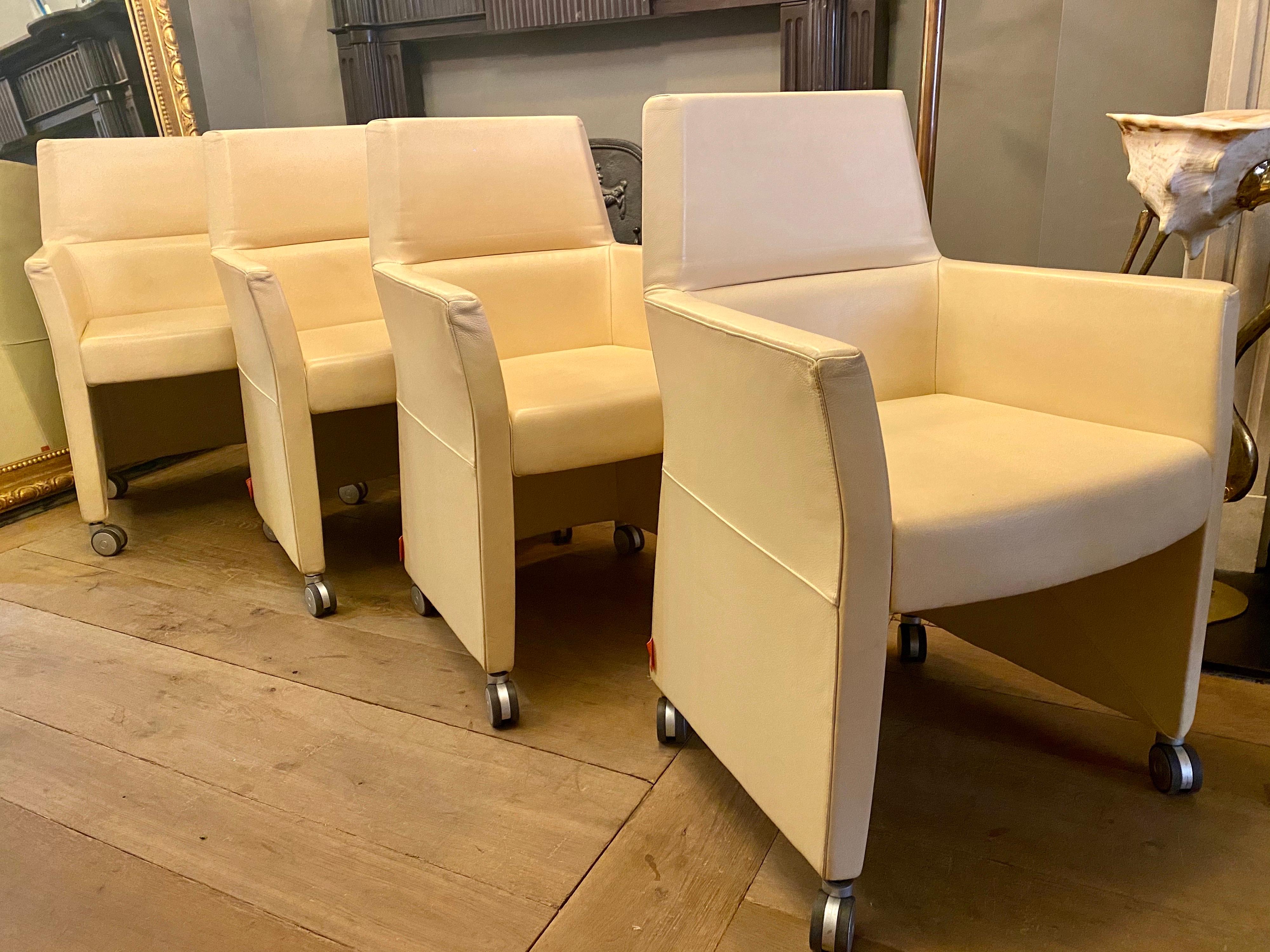 A set of four of white leather chairs on castors by Enrico Pellizzoni. Versatile and comfortable can be used as dining chairs, luxury office chairs or occasional lounge chairs. Labelled and in good order.