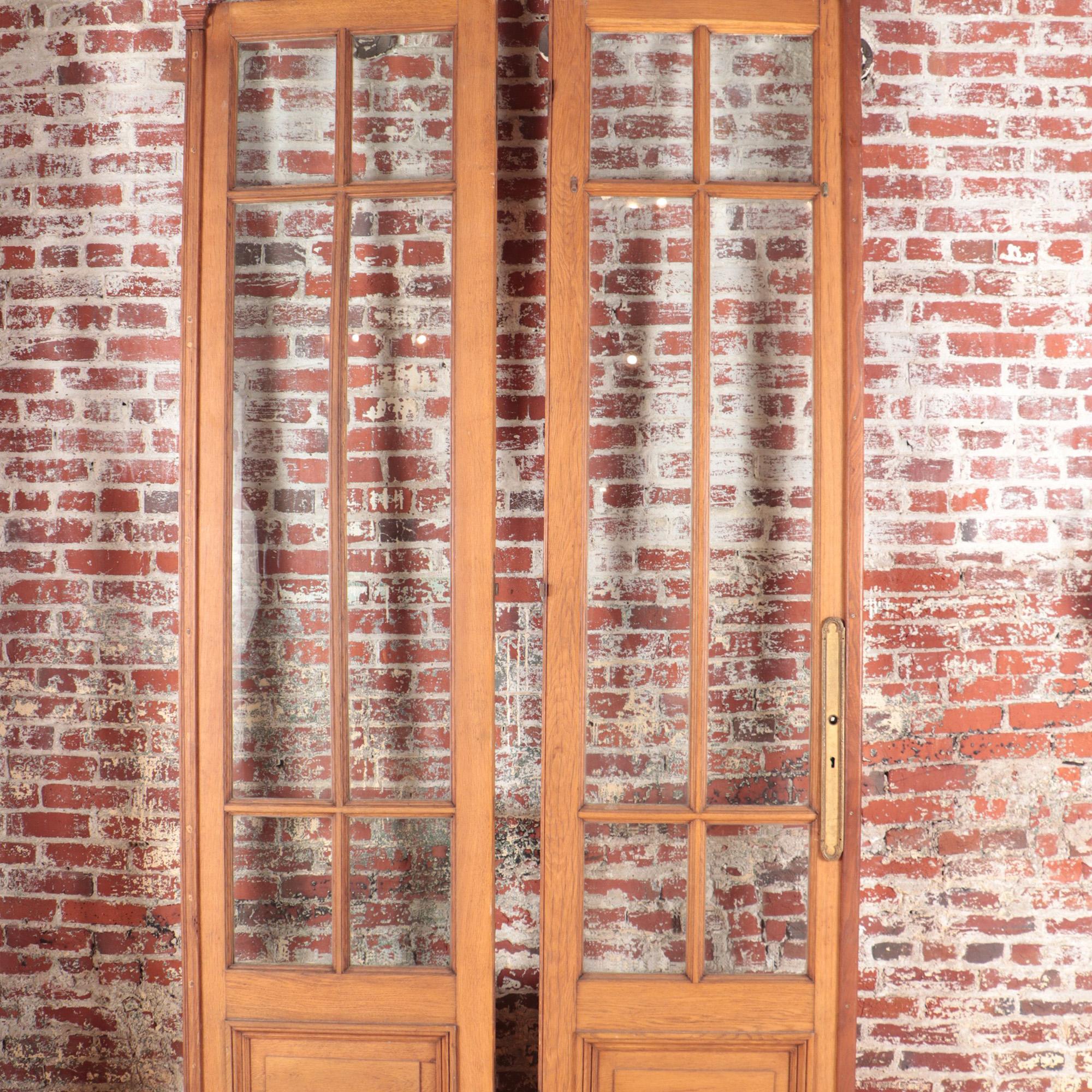 A set of four panel oak entry doors with beveled glass and bronze and iron hardware C 1900.