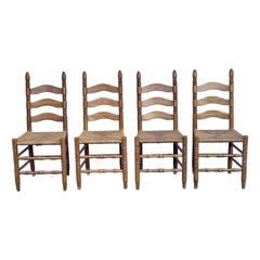 Conjunto de cuatro sillas de comedor rústicas vintage de roble y asiento de junco con respaldo de escalera