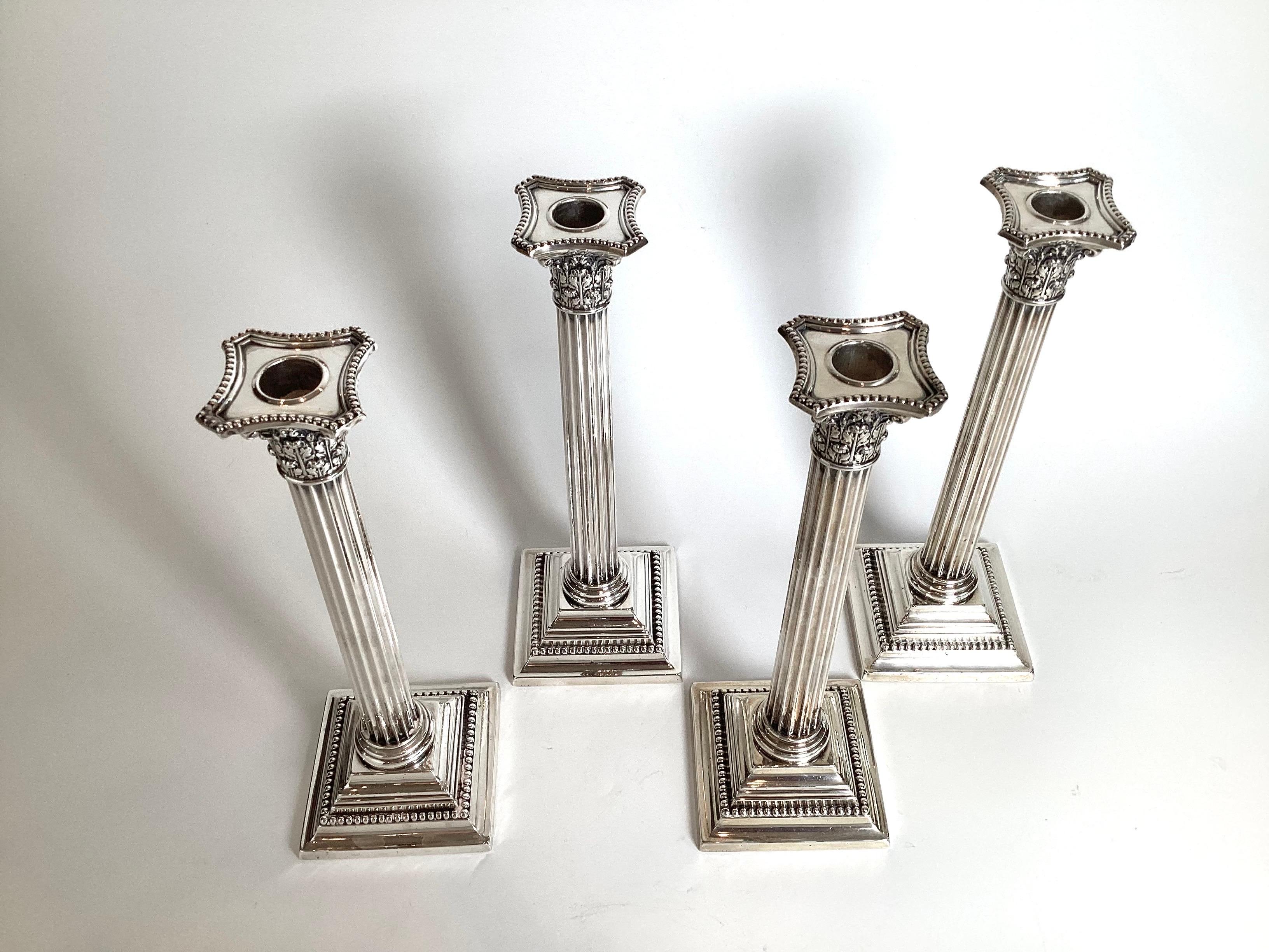 A set of four sterling silver corinthian column candlesticks.  Made int he first quarter of the twentieth century, these elegant neo-classical style candlesticks are a full 12 inches tall, each with their original bobeches.  Having the original set