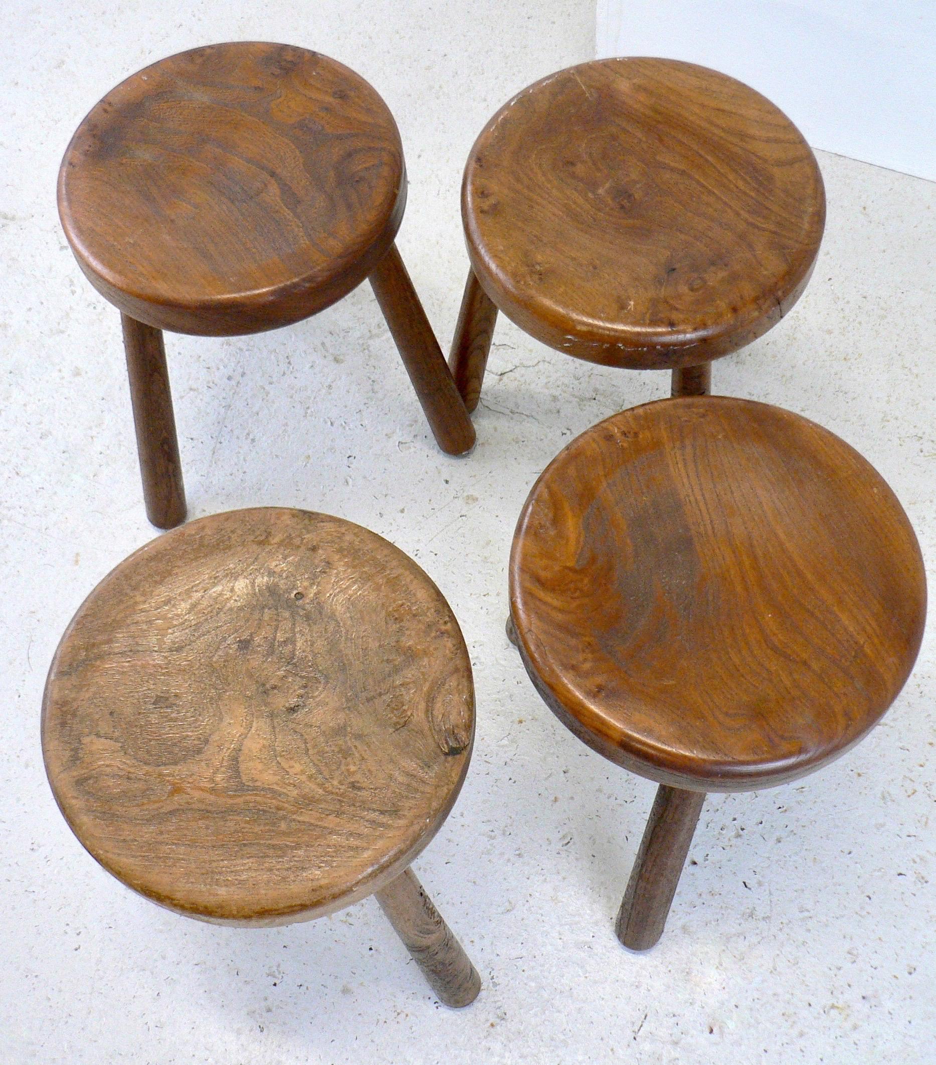 A set of four tripod 'shepherd' stools in the style of Charlotte Perriand. French craftsmanship from the mid-20th century, featuring a beautiful patina.