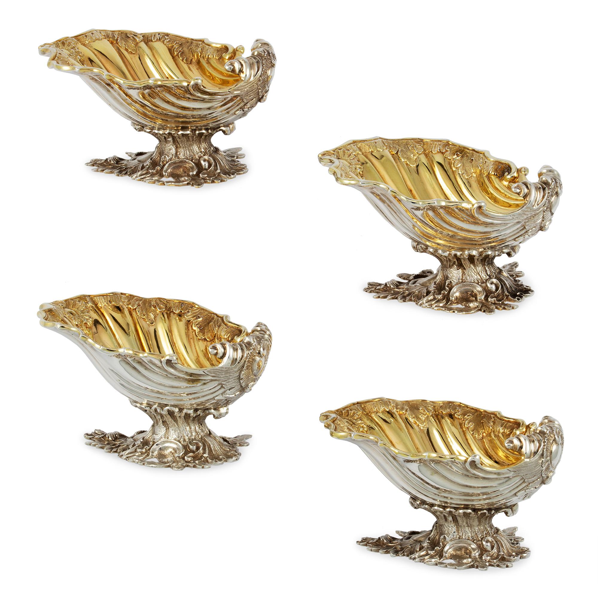 A set of four Victorian silver salt cellars, each designed as scallop shell bearing chased leaf decorations in the rim, with gold gilt interior and foliate design base, made by Daniel & Charles Houle, London 1853 & 1855, gross weight 28.5oz,