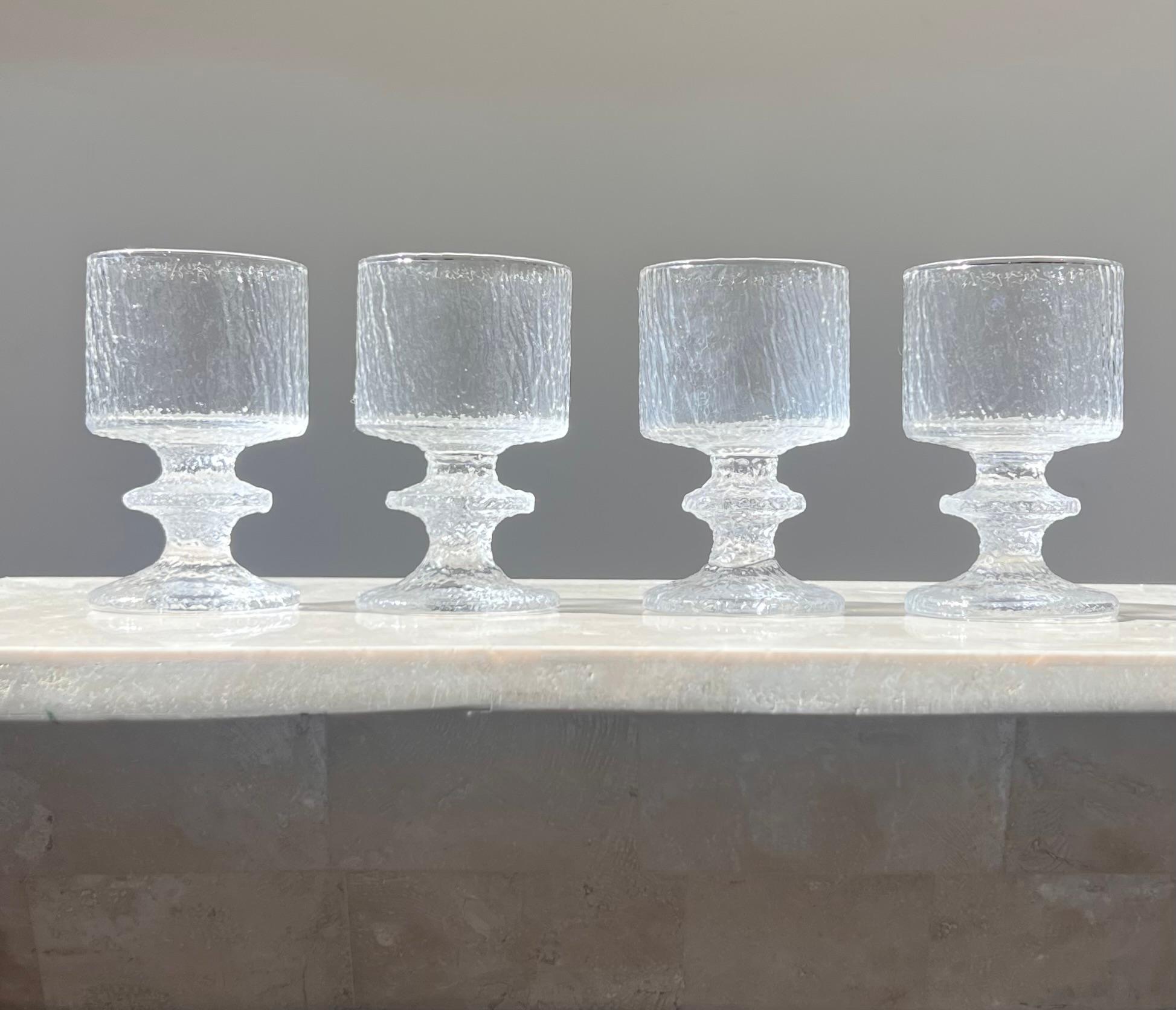 Set di quattro bicchieri da vino bianchi della metà del secolo scorso disegnati da Timo Sarpaneva per LASIA, Finlandia 1960. Questi bicchieri presentano uno speciale motivo ondulato simile alla corteccia di un albero, ma in vetro spesso lavorato a