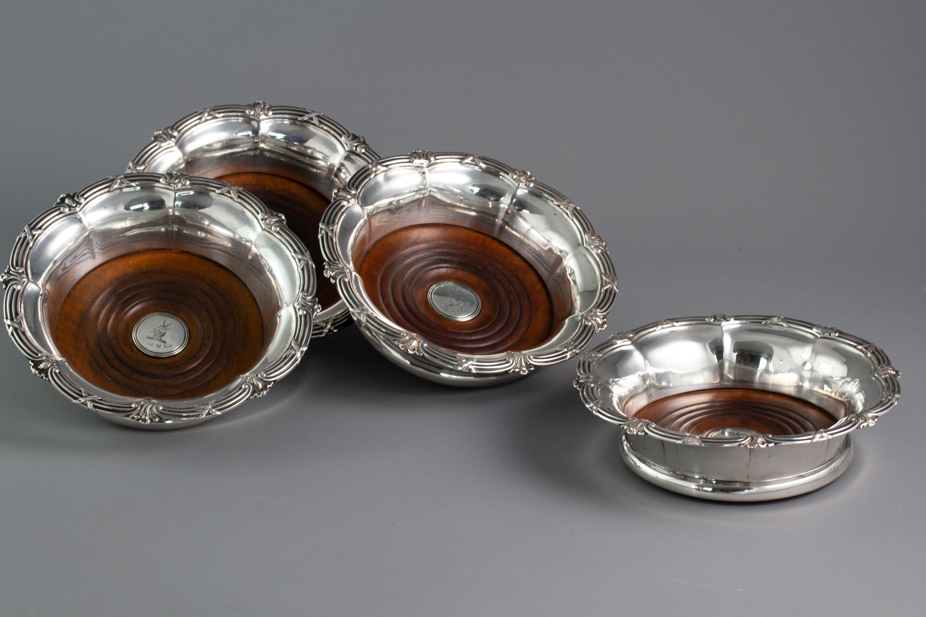 A very good set of four William IV silver wine coasters, of octagonal flared petal shaped form with a cast rim of ribbon and reed decoration and a shell at each node. The fruitwood bases with a central boss with the crest of a horned goat.

Marked