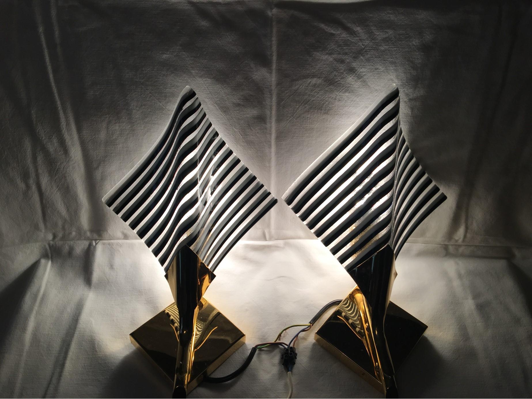 A lovely pair of sconces. Delightful, wall enhancing lights made of Gilten metal and beautifully black , white and clear striped glass. The aluminum reflectors over the bulbs help create a nice, indirect lighting effect. Each of the two fixtures