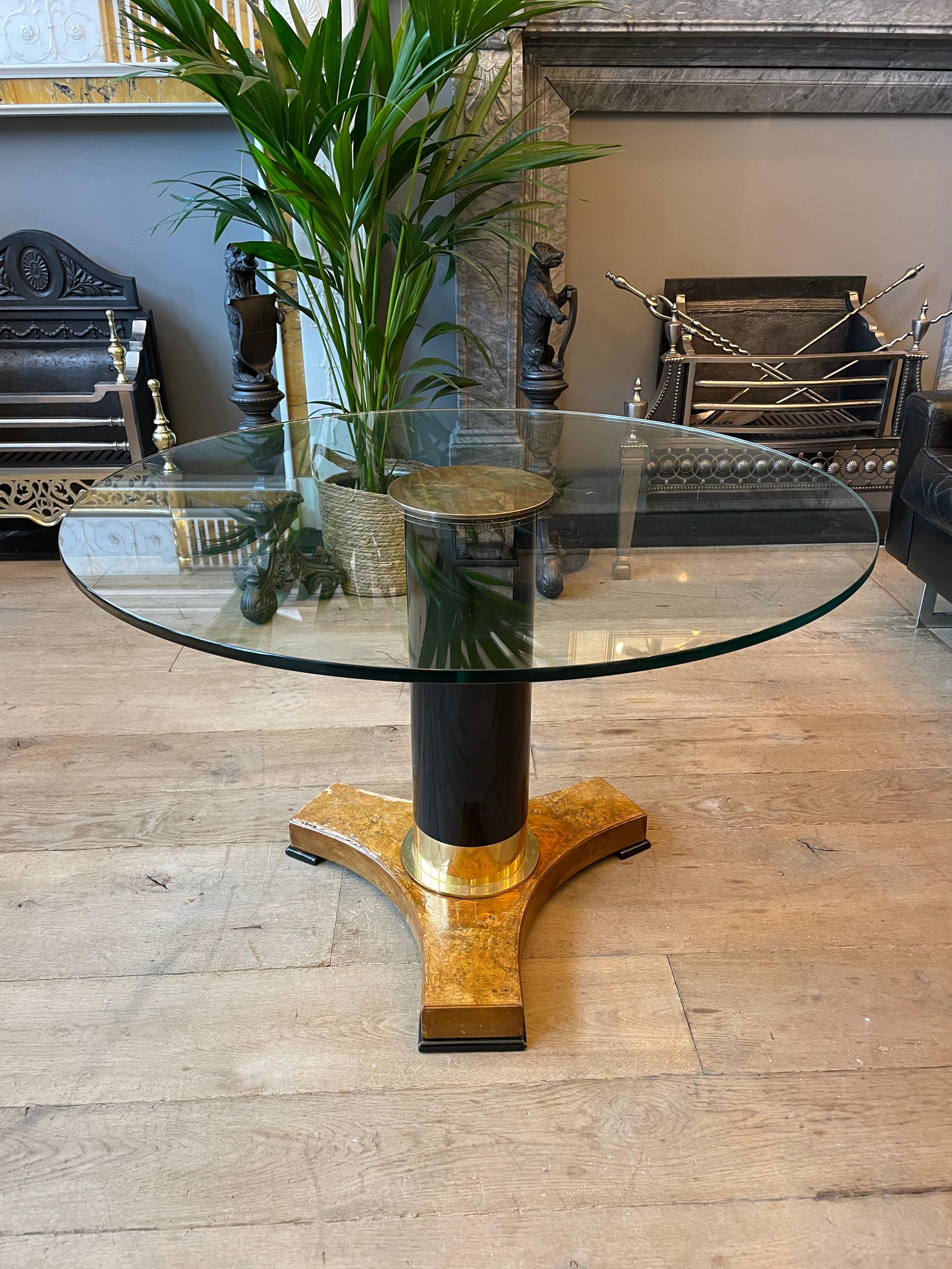 A set of circular tables one larger than the other, with Burr Walnut veneered bases, brass accents and ebonized supports. The brass centre screws in to hold the circular glass in place. One base more distressed than the other as seen in images,