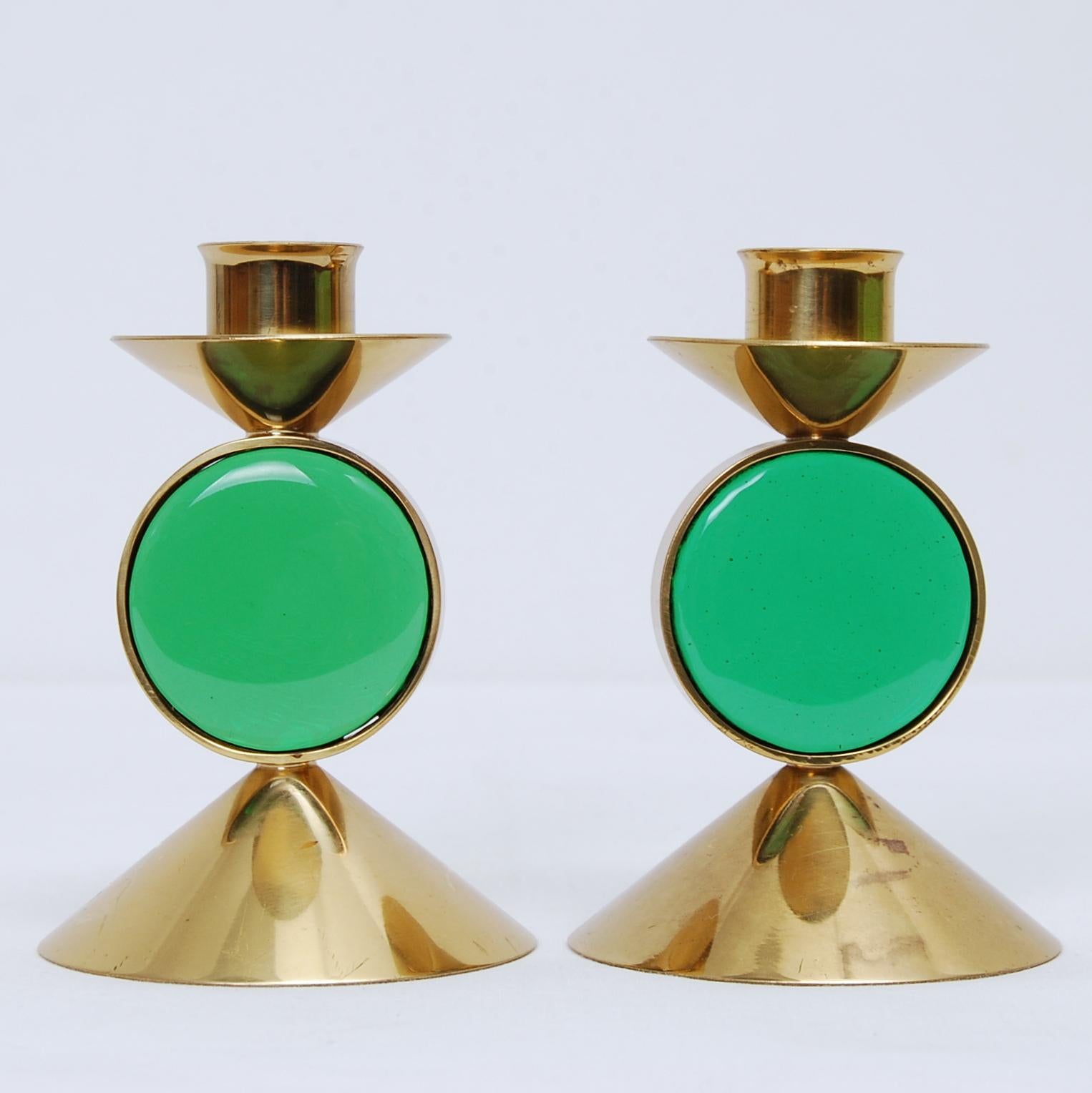 A pair of two Gunnar Ander candleholders in brass with mounted green art-glass. Manufactured by Ystad Metall. Stamped and signed.
 