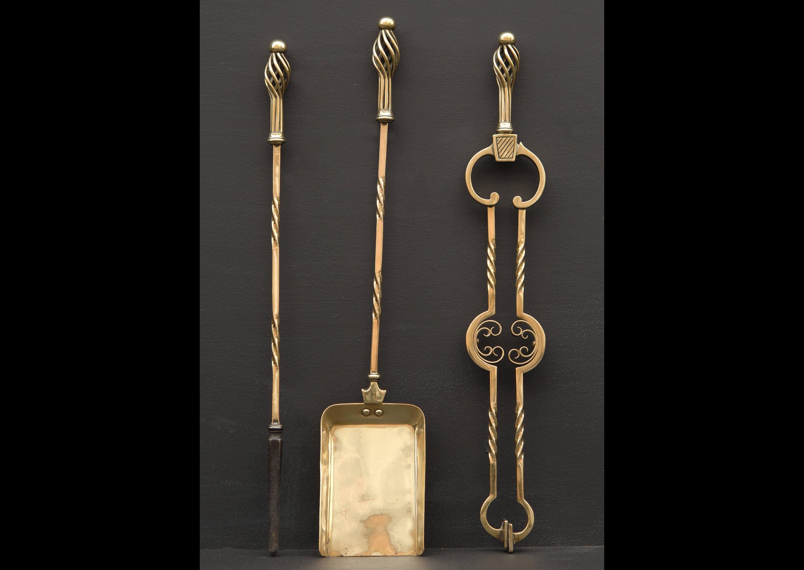 A set of late 19th century Arts and Crafts brass firetools, the square shafts with barley twist decoration, the finials with open basket weave, the tongs with formed scrolls, plain shovel.

Length:	685 mm      	27