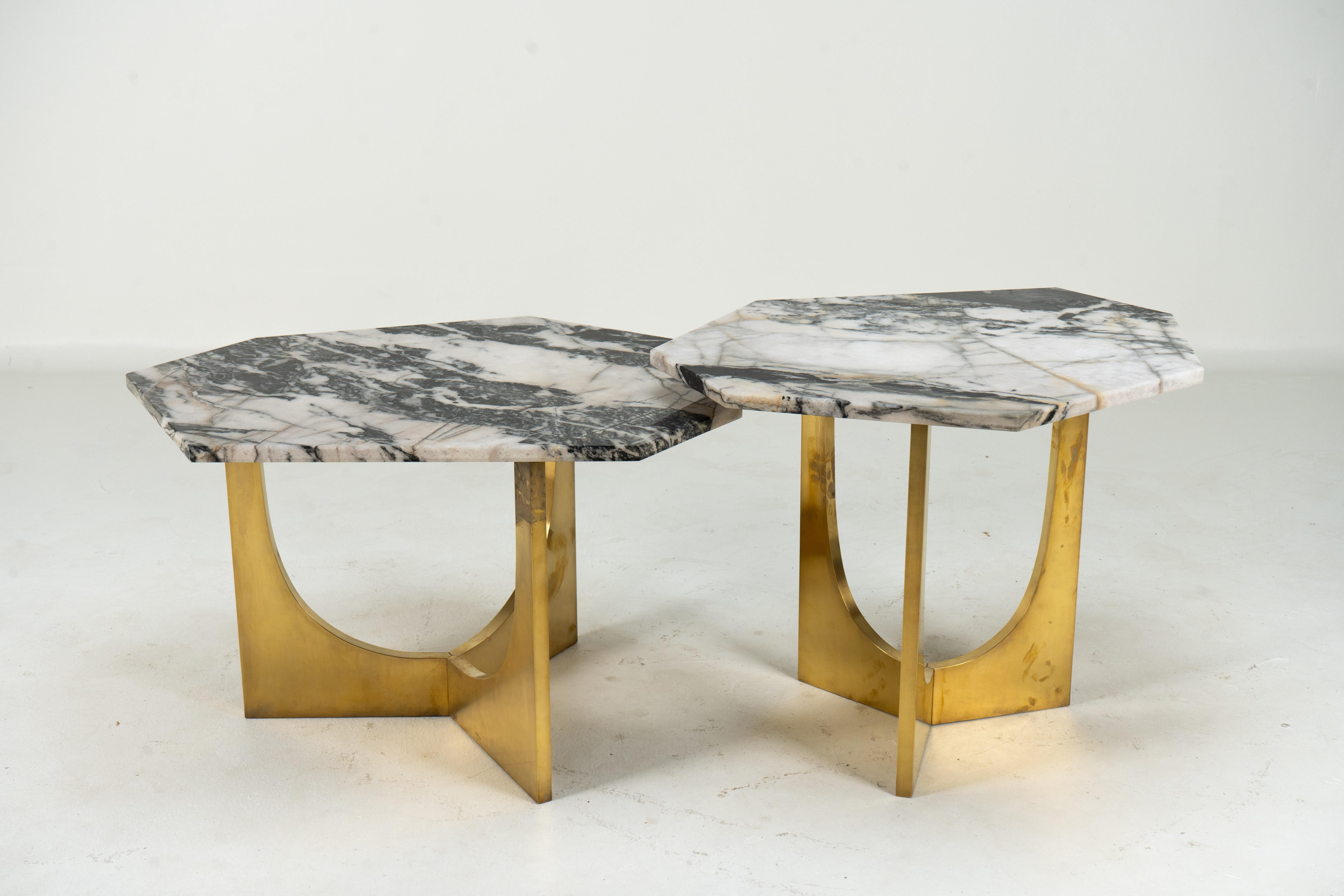 Cet ensemble de tables contemporaines d'inspiration brutaliste peut être utilisé séparément ou combiné pour former un ensemble de café à deux niveaux. Les bases métalliques légèrement incurvées contrastent élégamment avec les plateaux en pierre à