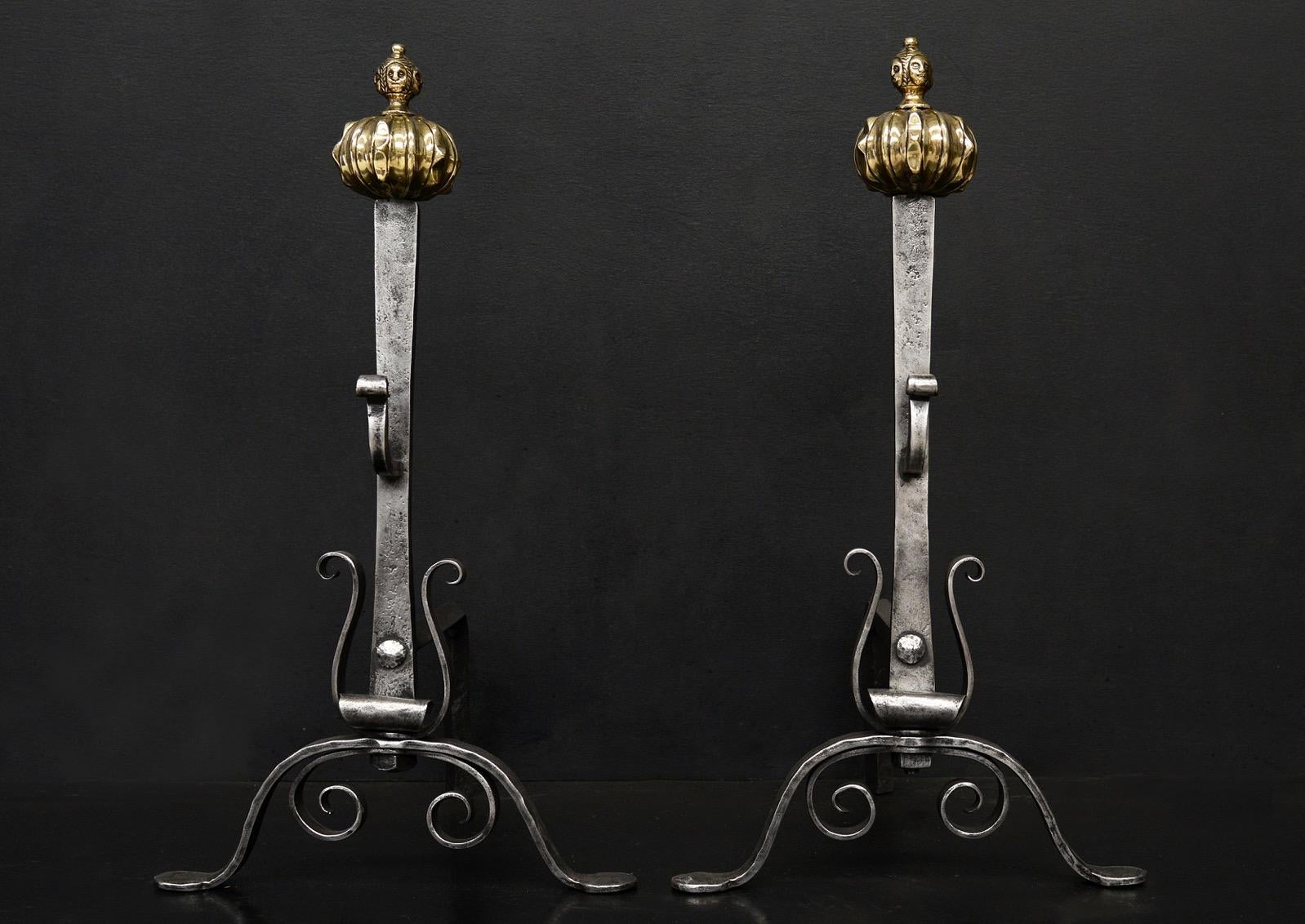 A set of polished firedogs. The scrolled polished wrought iron feet surmounted by scrollwork, shaped uprights and good quality brass finials engraved with figures. English, 19th century.

Height:	660 mm      	26