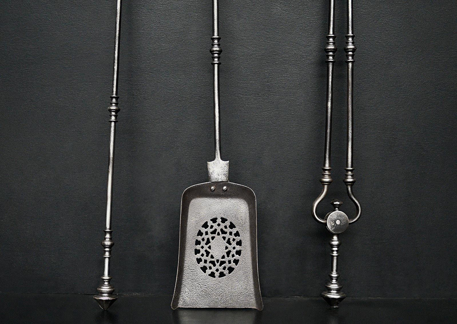 A set of polished steel firetools in the Georgian manner, with pierced pan and decorative finials above. English, early 19th century. 

Length:	770 mm      	30 ⅜