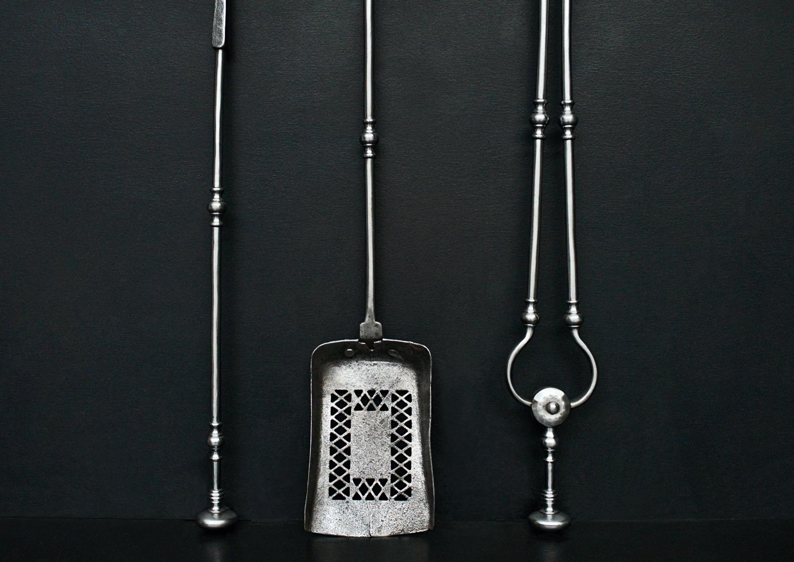 A good quality set of Georgian polished steel firetools. The rectangular pan pierced with diamond motif, the shafts with swells to centre and mushroom finials above. English, 19th century. 

Length:	720 mm      	28 ⅜