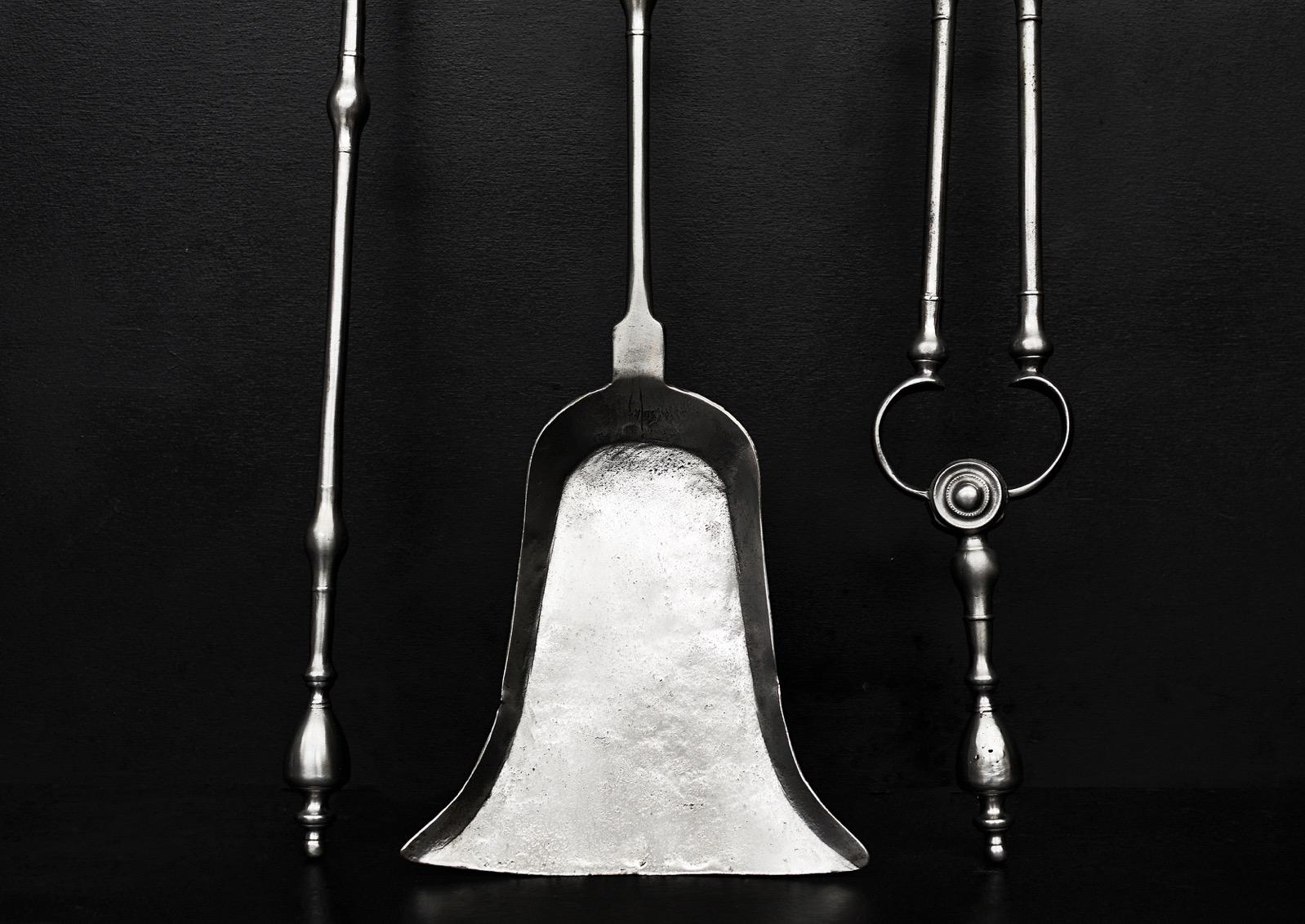 A set of polished steel Georgian firetools. The shafts with swells surmounted by urn finials. Rosette paterae to tongs. Elegantly shaped shovel. English, late 18th / early 19th century.

Length:	780 mm      	30 ¾