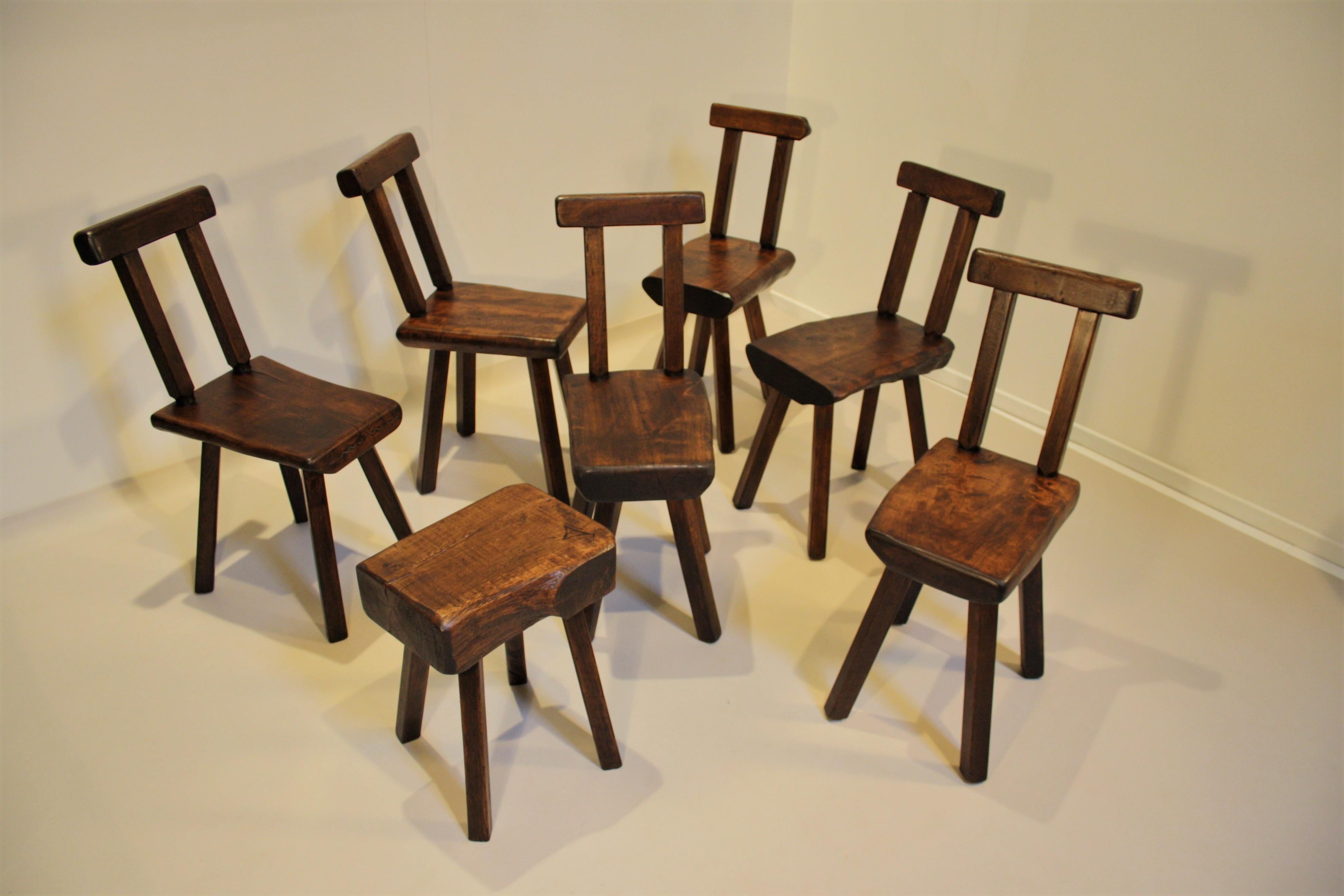 Six Belgian hand carved oak chairs and one stool made of solid oak with natural irregular edges.
The solid oakwood shows some knots and cracks, this gives the whole a very beautiful look.
At one of the chairs, a metal spiral was originally