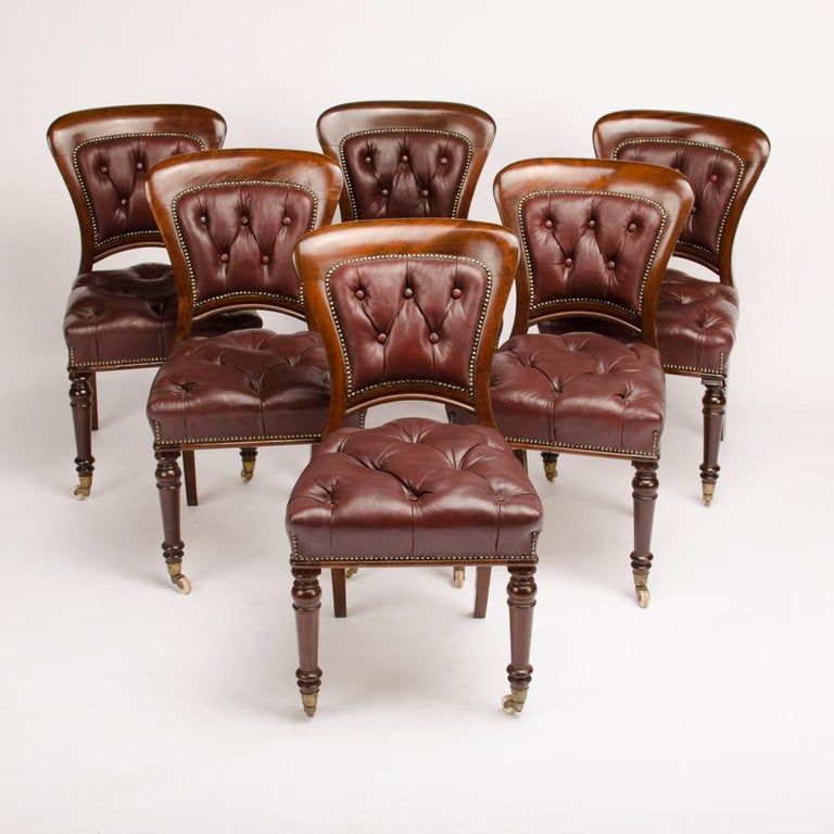 A set of six 19thC Irish walnut chairs, upholstered in dark brown tufted leather. The padded back and seat finished with antique brass studs. Seat is raised on two turned legs in the front terminating in casters. Chairs are branded by the maker