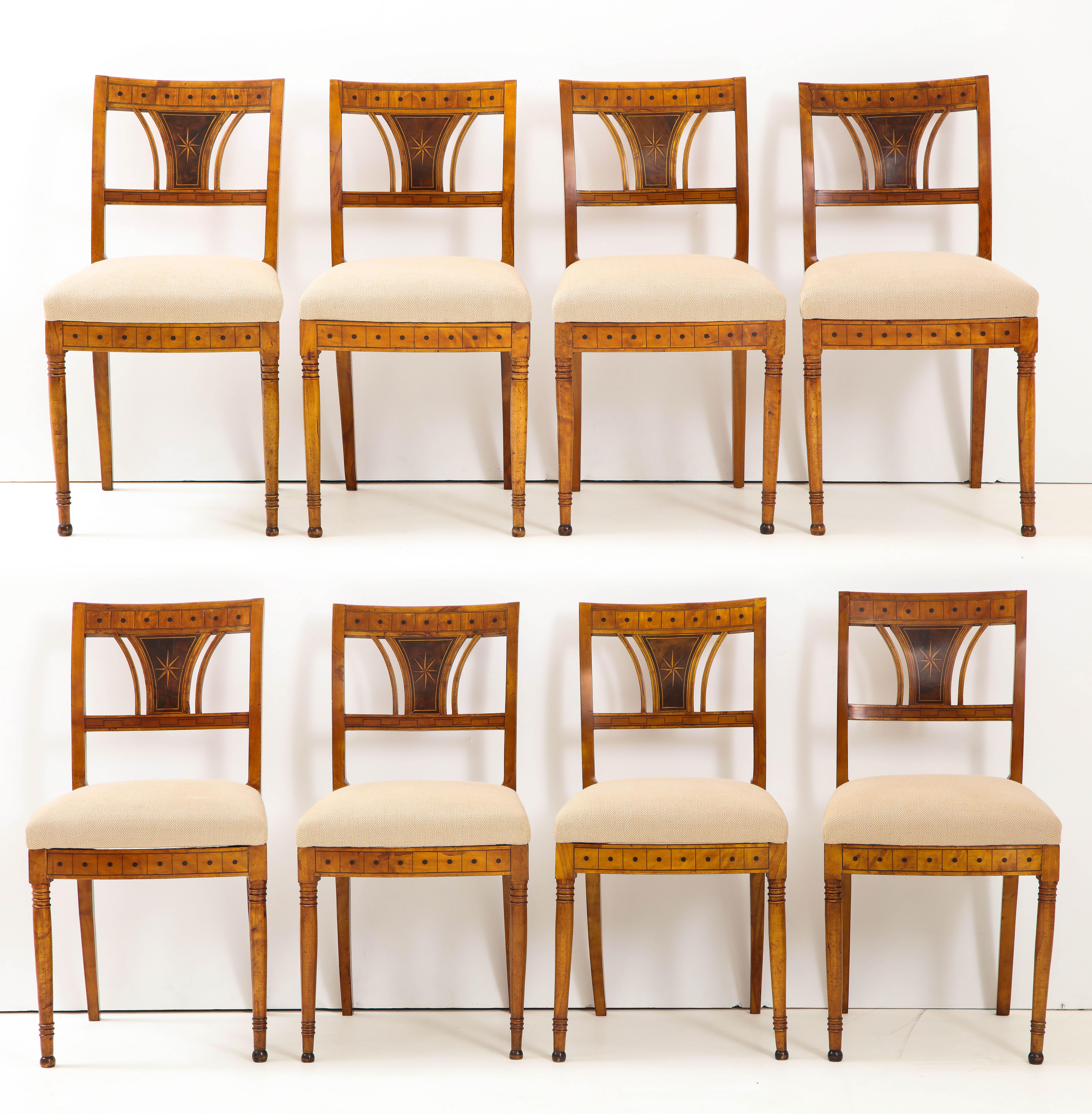 A good set of eight Danish Empire inlaid birchwood sidecars, circa 1810-1820, each with a rectangular backrest, upholstered seats and raised on circular tapered legs. Geometric mahogany and ebony inlays throughout. Previously with cane seats now